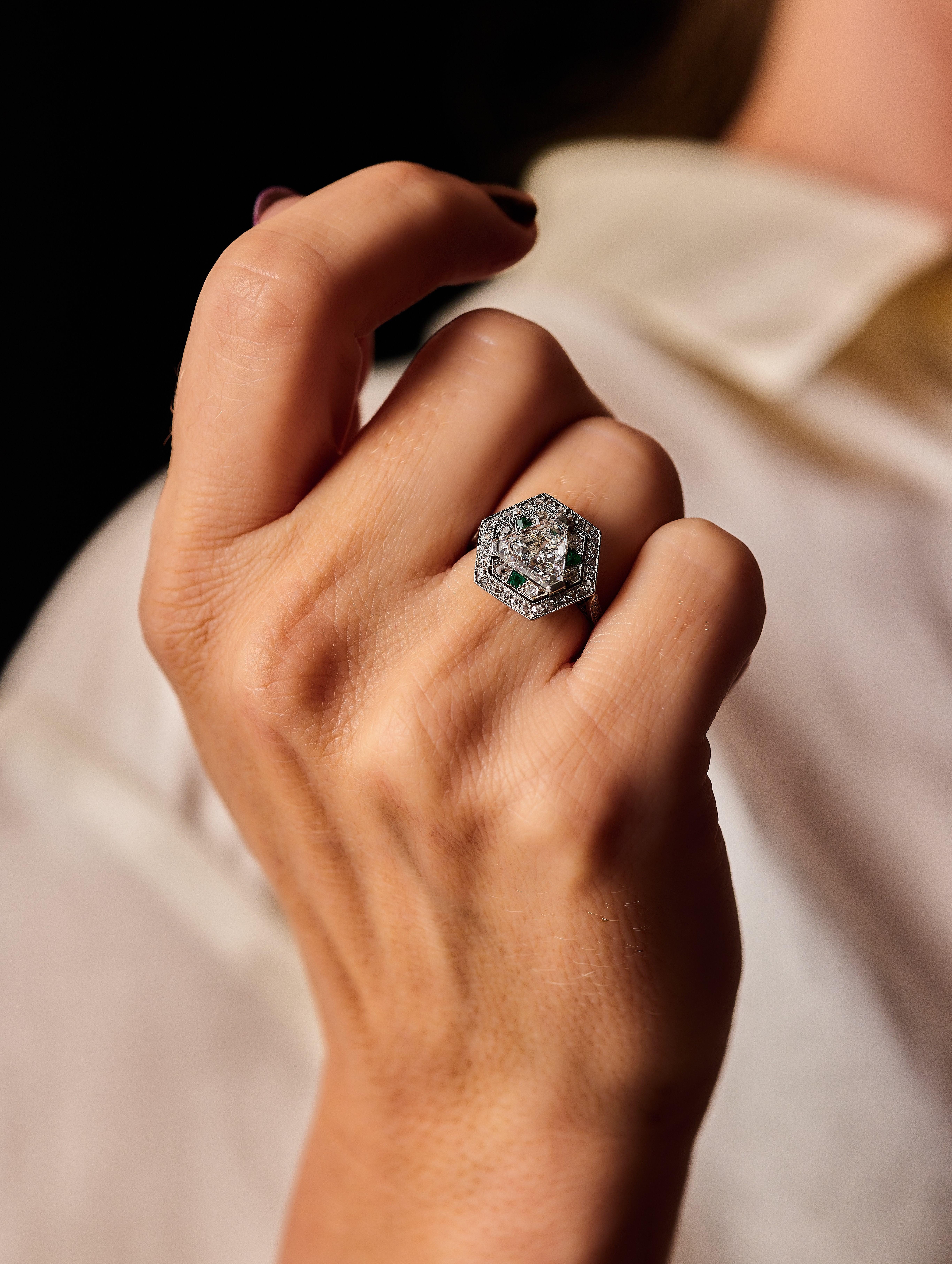 Une déclaration de mode avant-gardiste, luxueuse et raffinée. 

Bague hexagonale finement ajourée en platine 850 millièmes, sertie d'un diamant triangulaire en serti griffe dans un double entourage de diamants de taille ancienne et de taille 8/8,