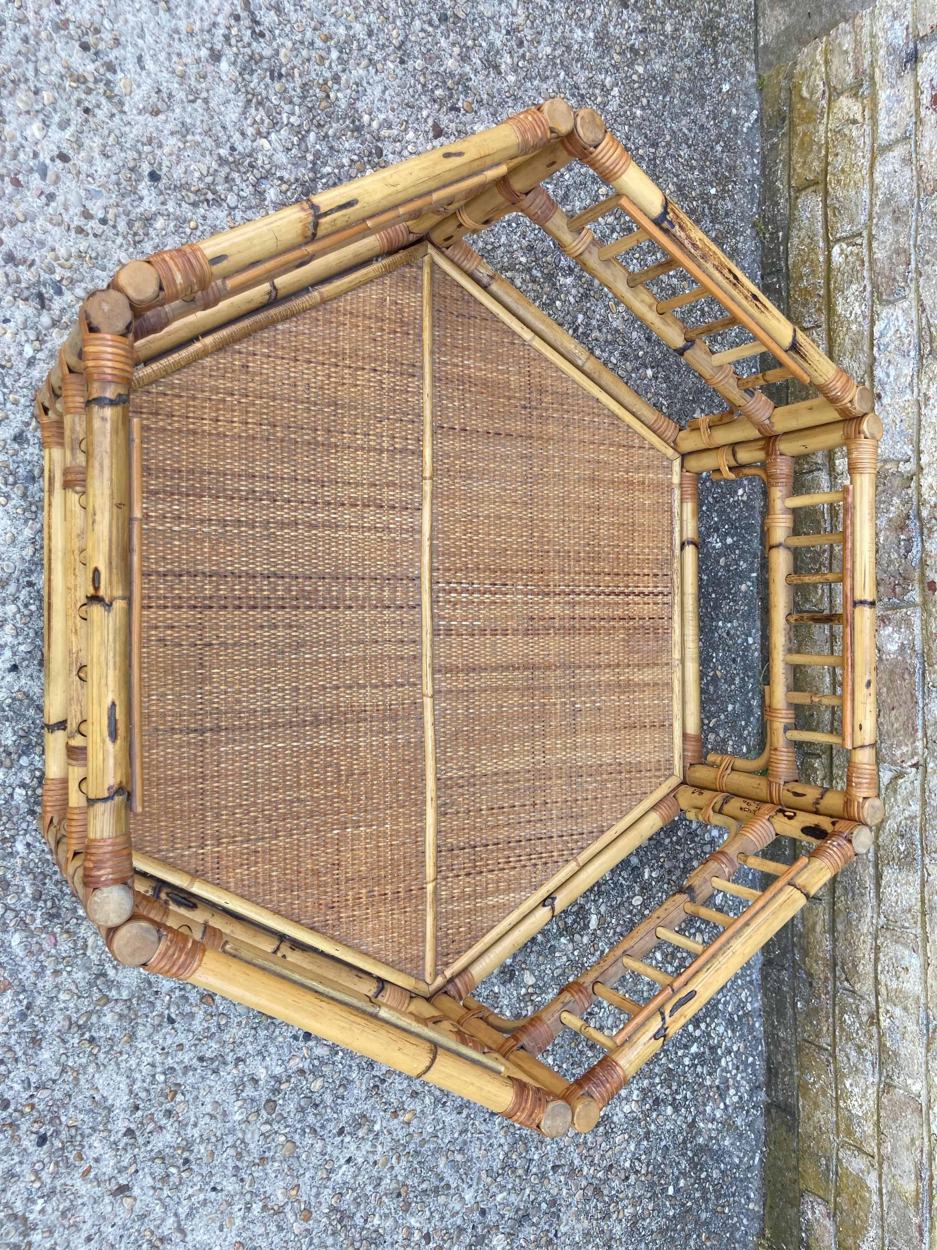 Hexagonal shaped bamboo coffee table with rattan under shelf and lightly tinted glass top.