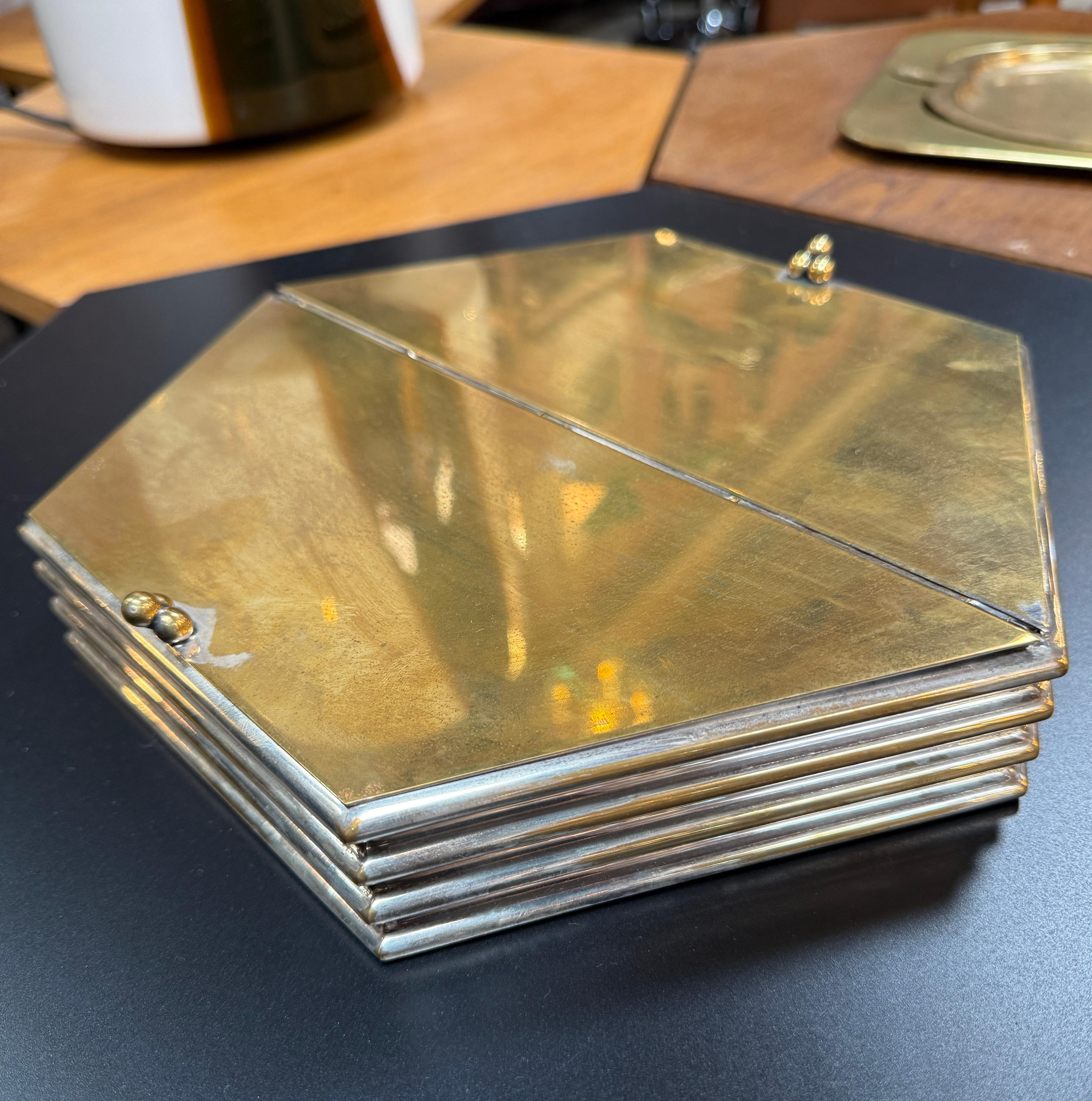 Diese einzigartige sechseckige Deko-Box kombiniert eine elegante geometrische Form mit einer Mischung aus warmen und kühlen Tönen. Das Äußere besteht aus einem Deckel aus poliertem Messing, der mit versilberten Rändern akzentuiert ist und ein