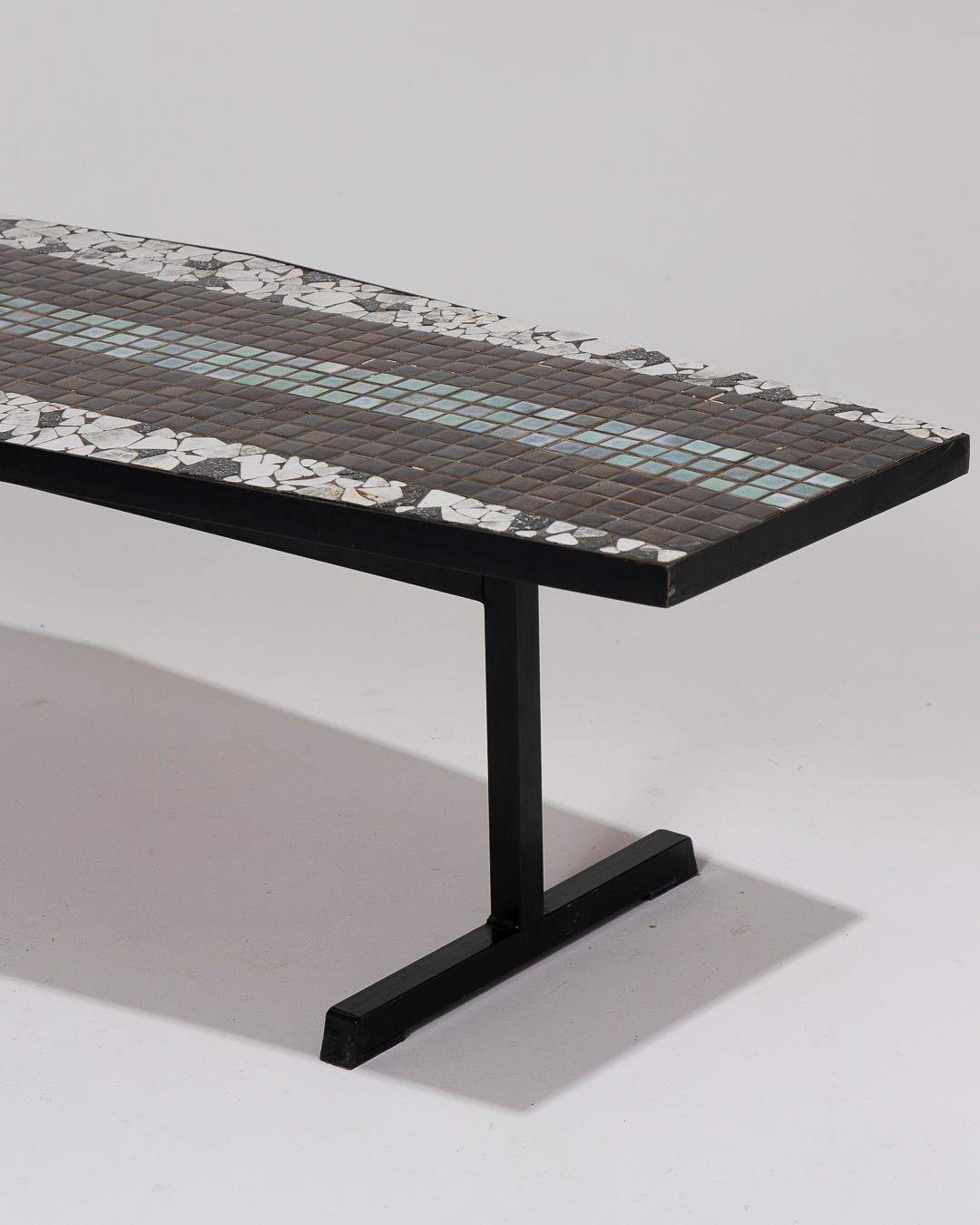 Table basse dotée d'un plateau hexagonal incrusté de carreaux de céramique blancs, noirs, verts et bleus. La table repose sur deux pieds en forme de 