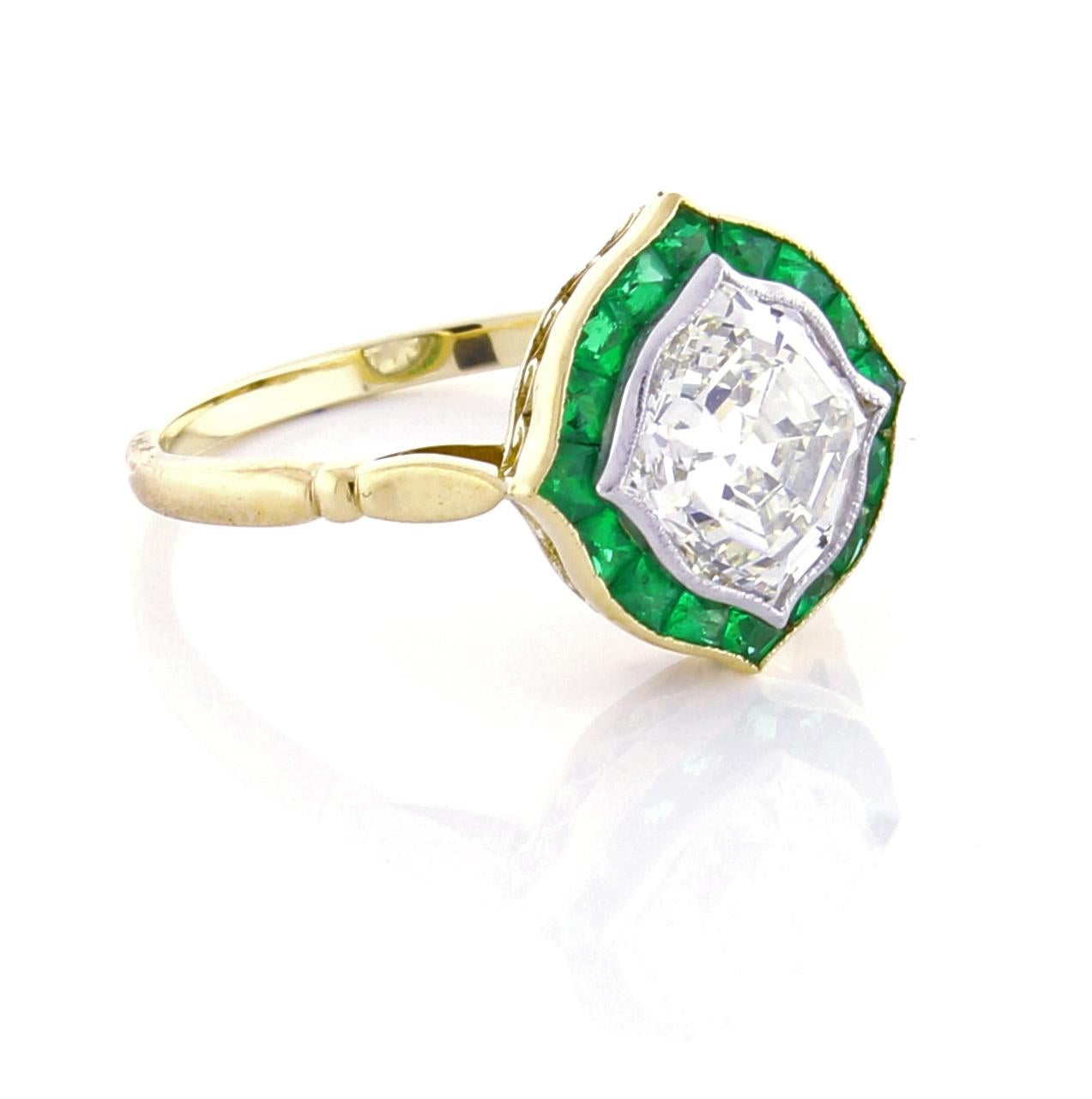 An unusual antique hexagonal shaped diamond is framed in six pointed bowed hexagonal platinum setting surrounded by meticulously calibrated fine emeralds. The ring is handmade in 18 karat gold. The diamond is approximately 1.80 carats, K color and