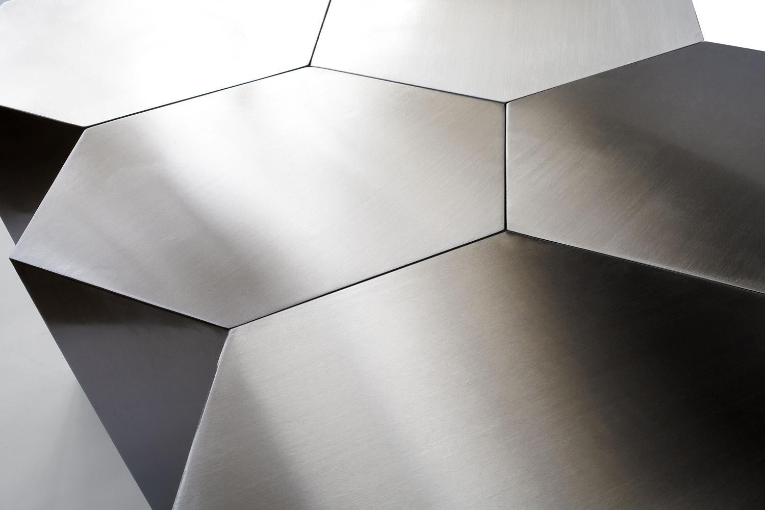 The Hex table explores systemic ordering and modular relationships: each stainless steel pod fits precisely alongside others, offering infinite possibility for the table's ultimate configuration and size. While embracing the modern need for