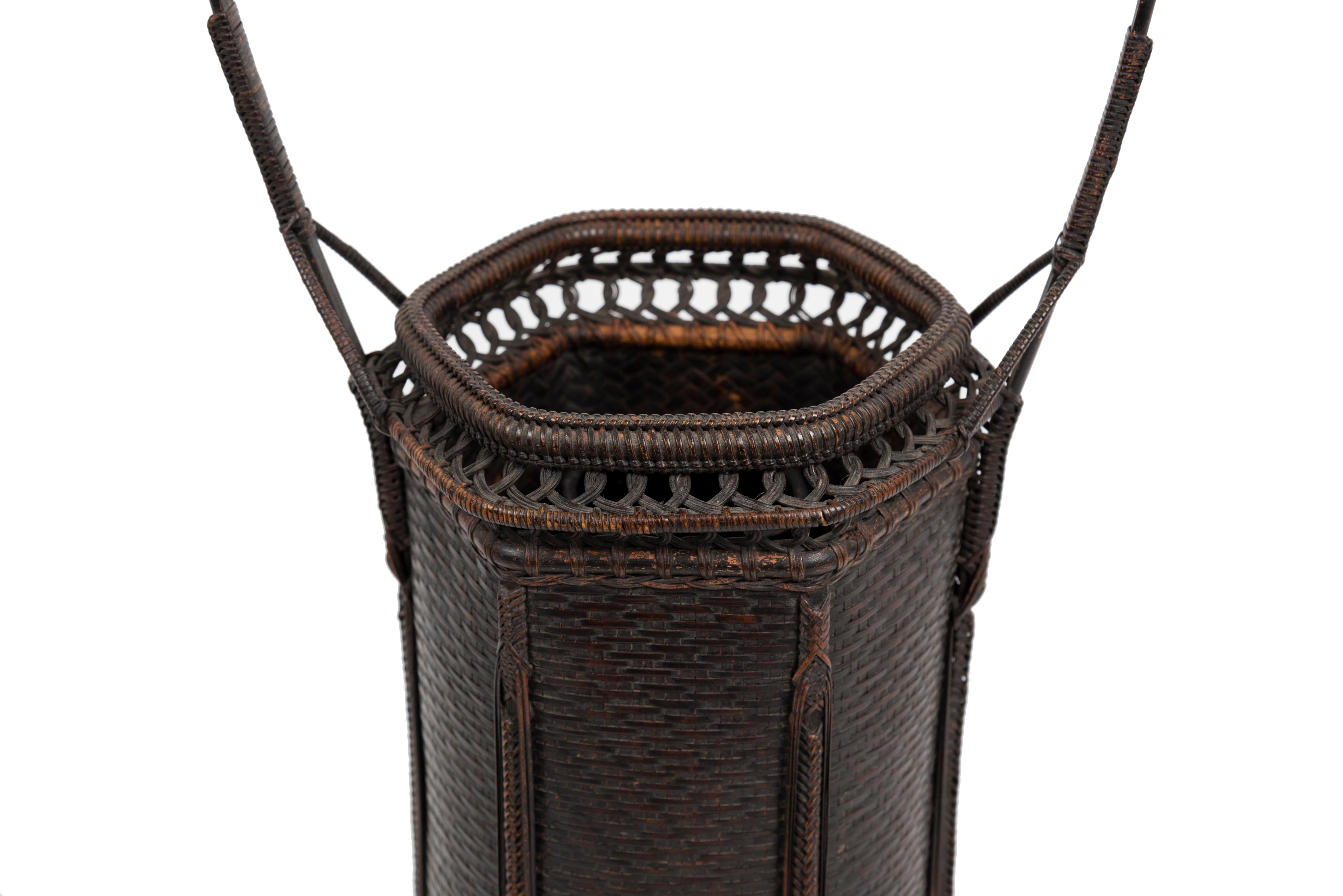 Sechseckiger Hanakago-Korb aus Rattan und Bambus im chinesischen Stil für Ikebana (Karamono-Hanakago). Sie besteht aus einer lackierten und gebürsteten Bambusvase.
Der Körper ist horizontal eng geflochten, die Ränder sind durch vertikale Flechtung
