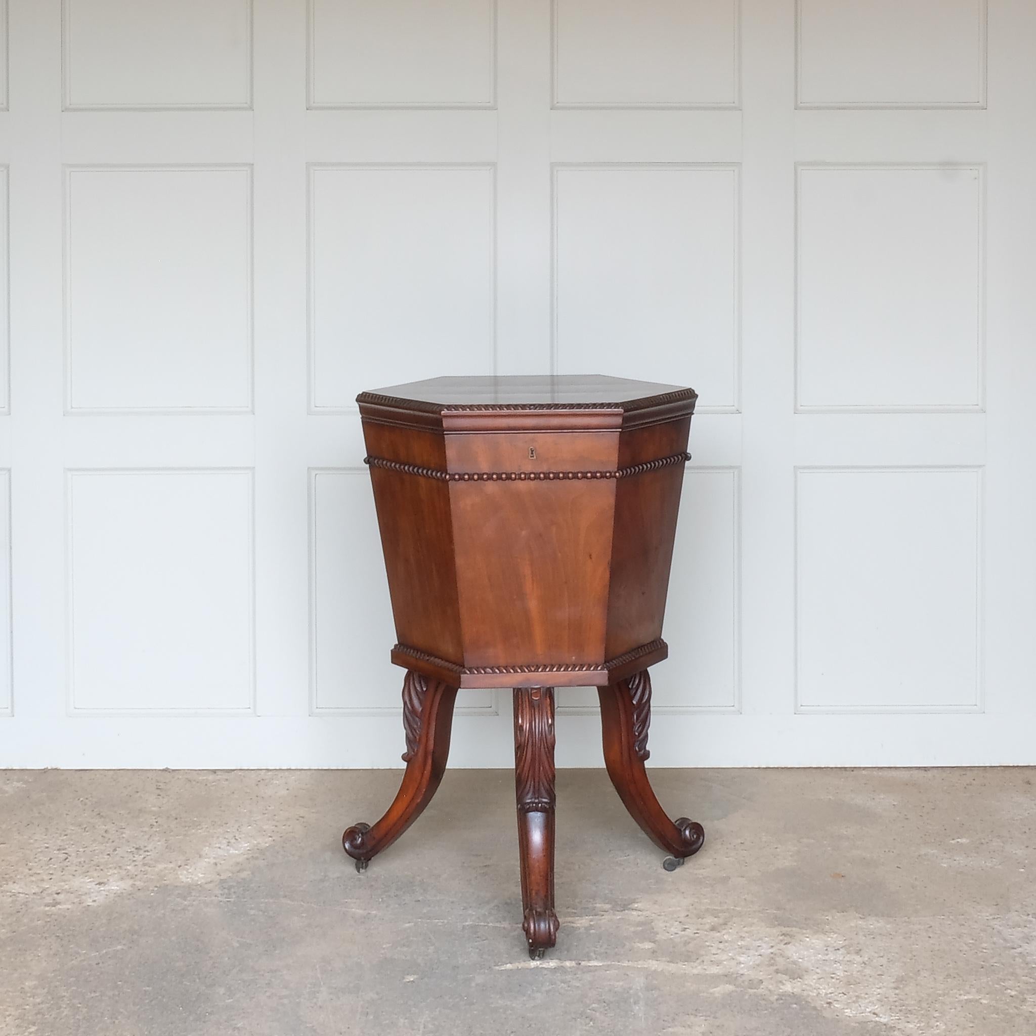 A hexagonal mahogany wine cooler, 19th century, with a hinged moulded top, enclosing a tin-lined interior with divisions for six bottles, on elegantly detailed cabriole legs with scrolls at the feet and a drainage tap underneath, in very good