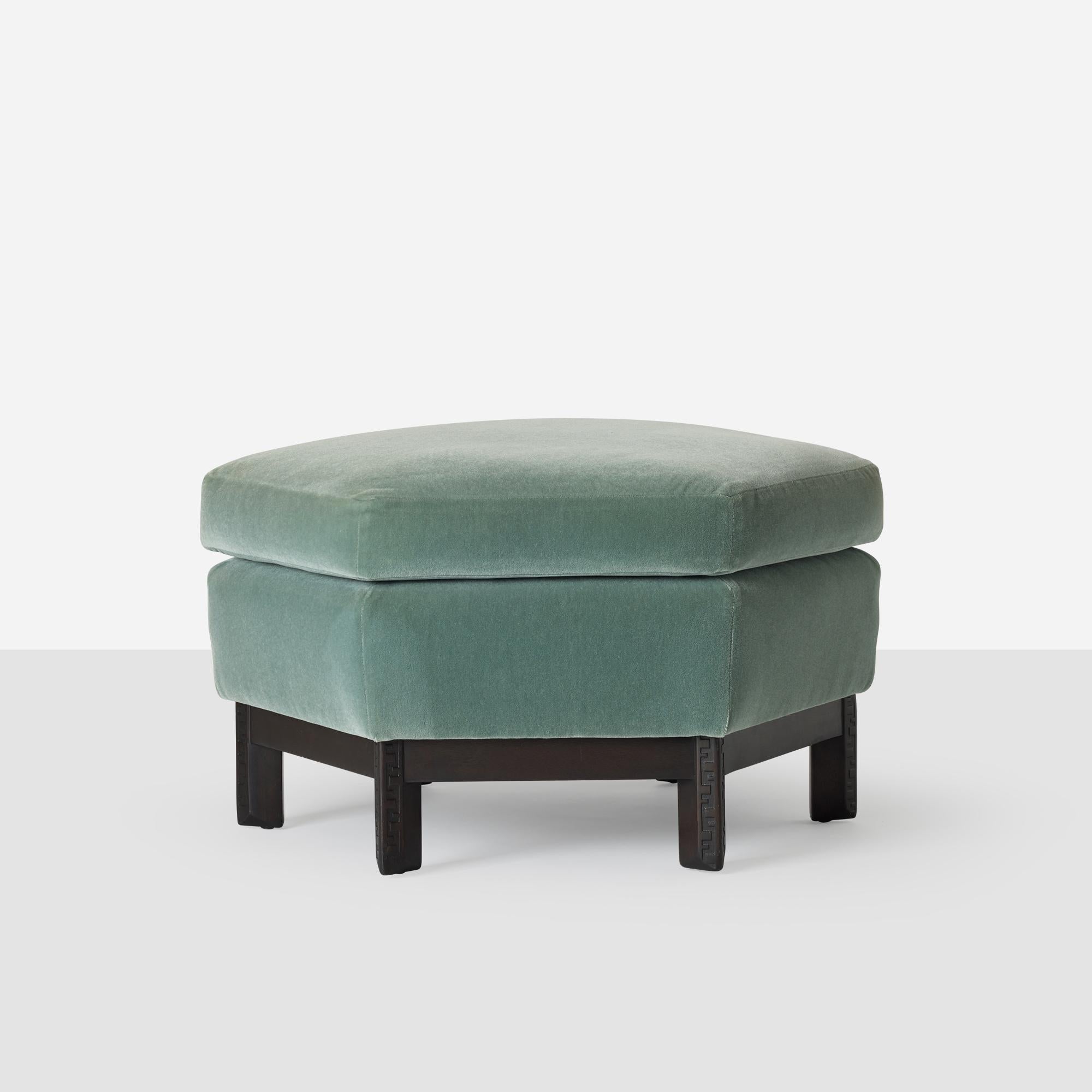 Una otomana hexagonal diseñada por Frank Lloyd Wright para la colaboración Heritage-Henredon. Presenta una base de caoba con patas facetadas y detalles tallados Taliesin, rematada con un mullido cojín tapizado en mohair verde salvia. Ligero desgaste