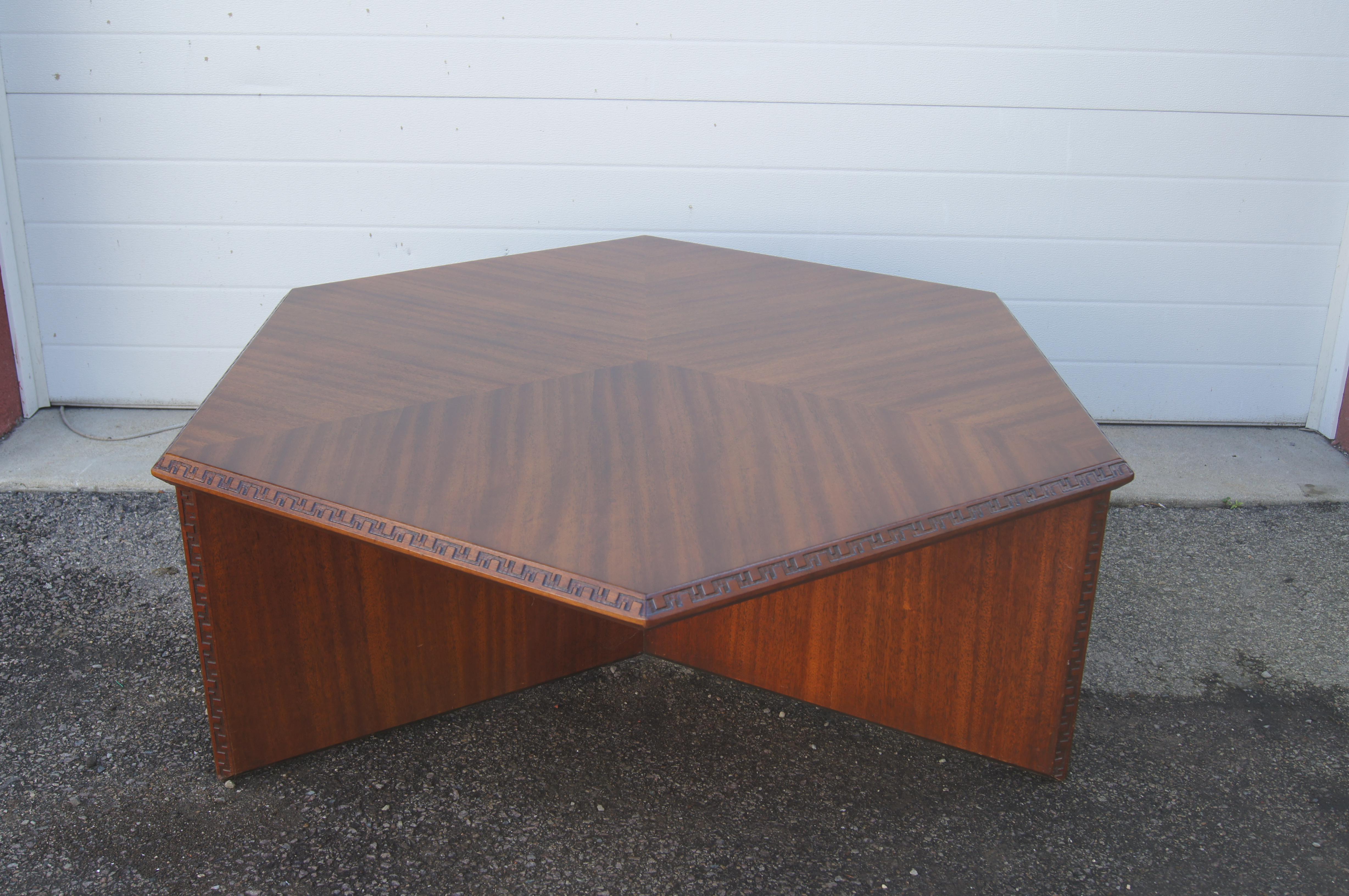 Part of the Taliesin collection that Frank Lloyd Wright designed for Henredon in 1955, this mahogany coffee table features a hexagonal top on a tripod base edged at the top with a dentil design from Taliesin. 

The designer's signature stamp is