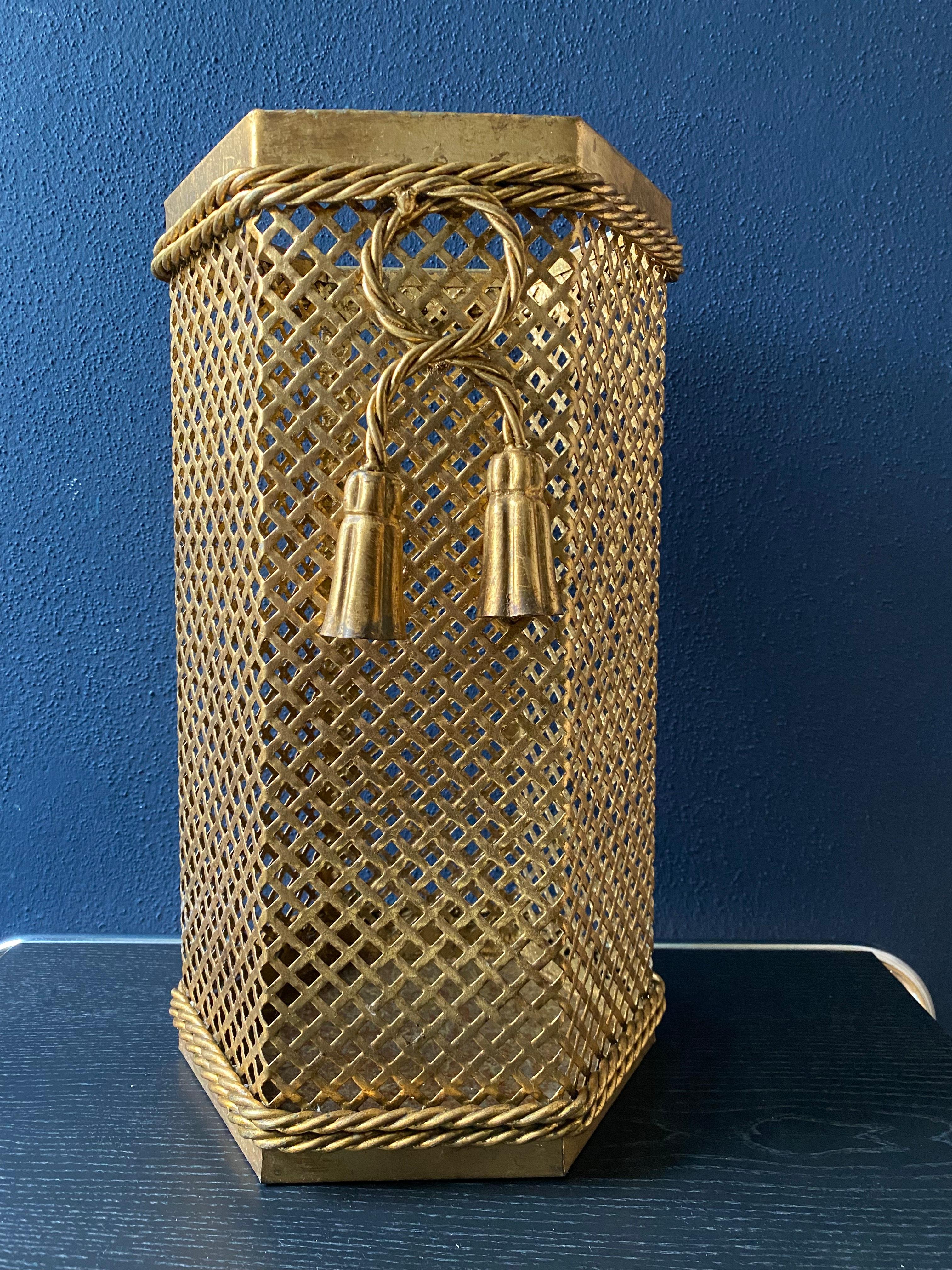 This hexagonal umbrella stand by Li Puma hails from Florence, Italy, and was manufactured in the 1950's,

While clearly identifiable as a Li Puma umbrella stand, with its typical perforated lattice pattern, bent rope and tassel detail and gold tone