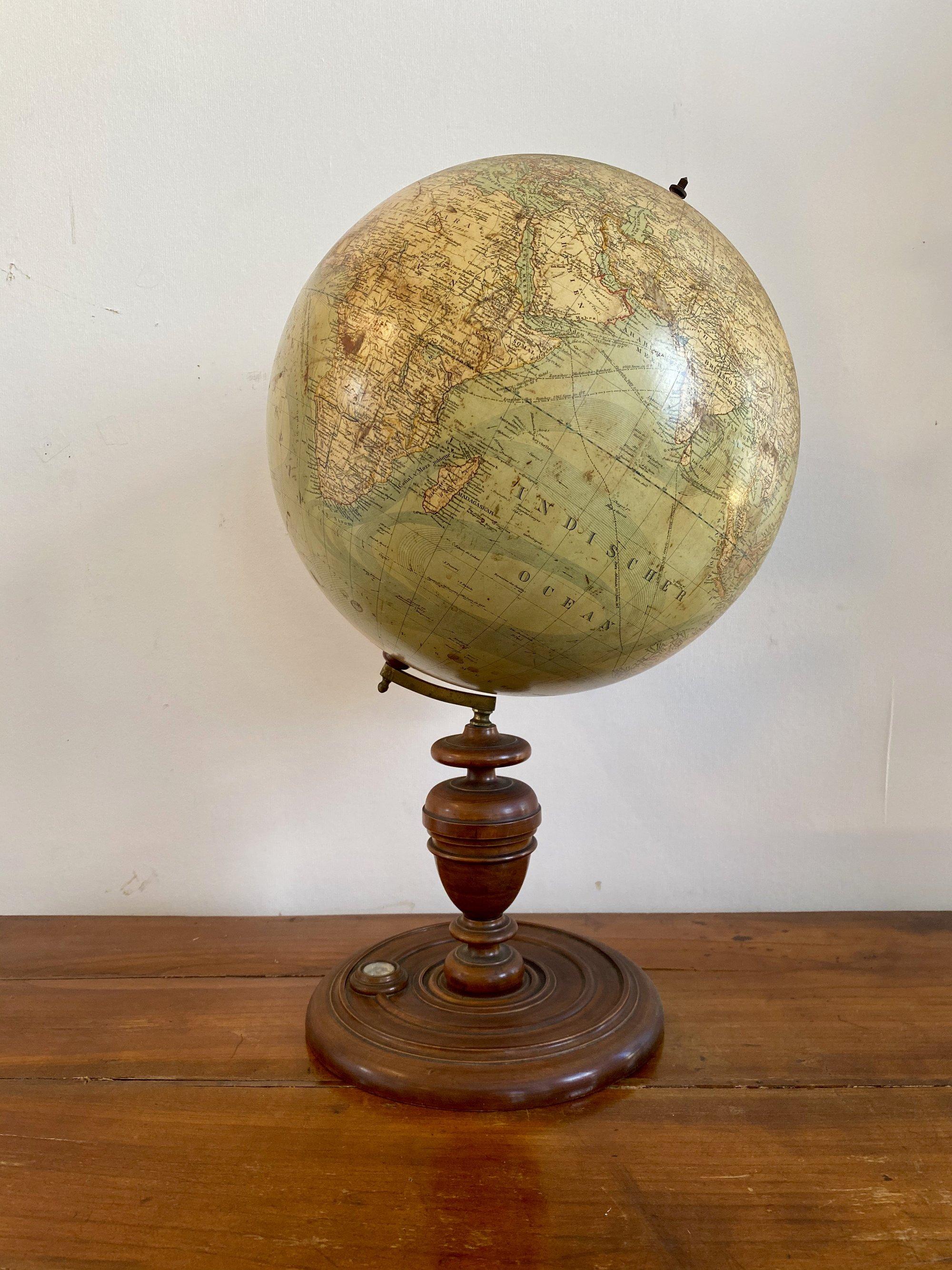 A 24 inch highly detailed terrestrial globe with compass by Ludwig Julius Heymann, Berlin, circa 1885. The globe made up of twelve chromolithographed gores, the oceans showing ocean currents, on turned fruitwood finial with inserted compass, raised