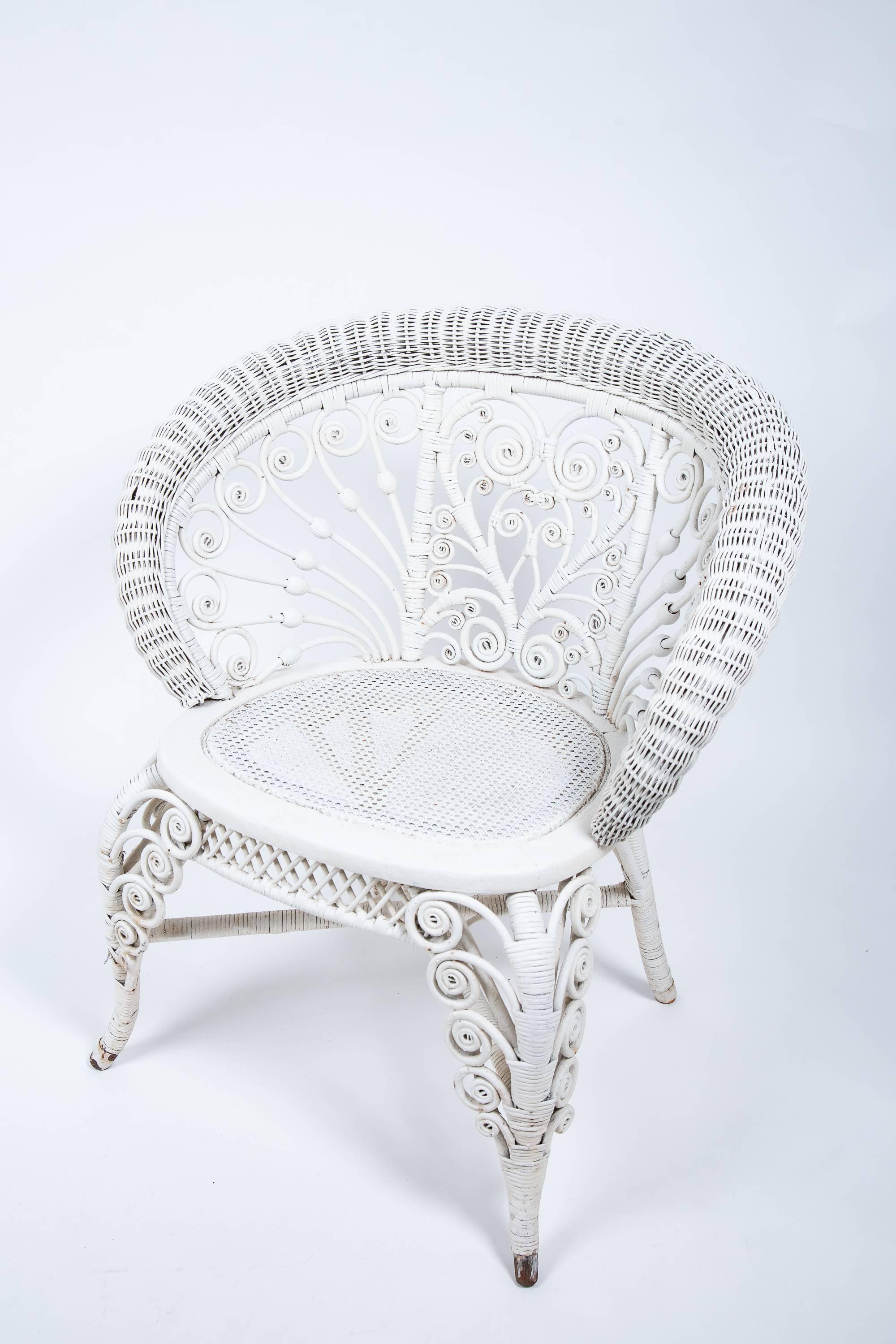 Pair of Victorian white painted wicker parlour chairs. Hand crafted intricate heart design back, and curved wicker leaves climb the front legs. 
Wonderful parlour, sunroom, or patio set.