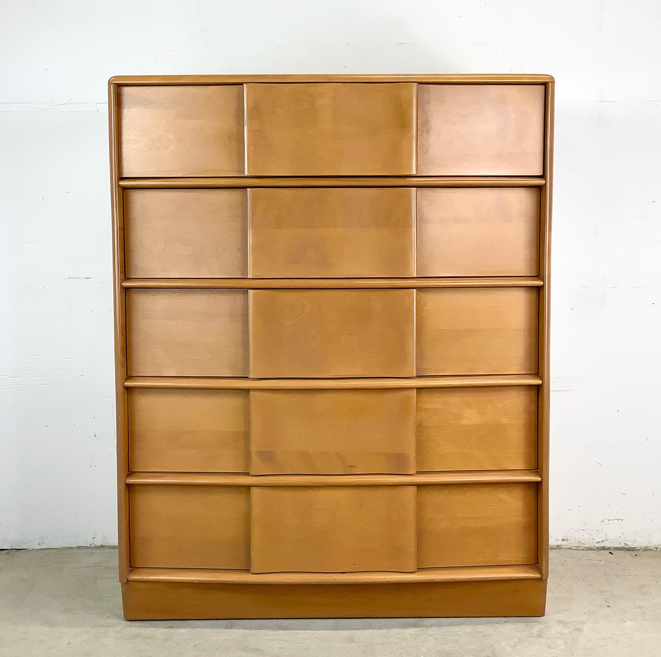 Add a touch of vintage charm and functionality to your bedroom with this Heywood Wakefield five-drawer highboy dresser, a beautifully crafted mid-century piece finished in the brand’s beloved champagne stain. With its warm wood tones, sleek lines,