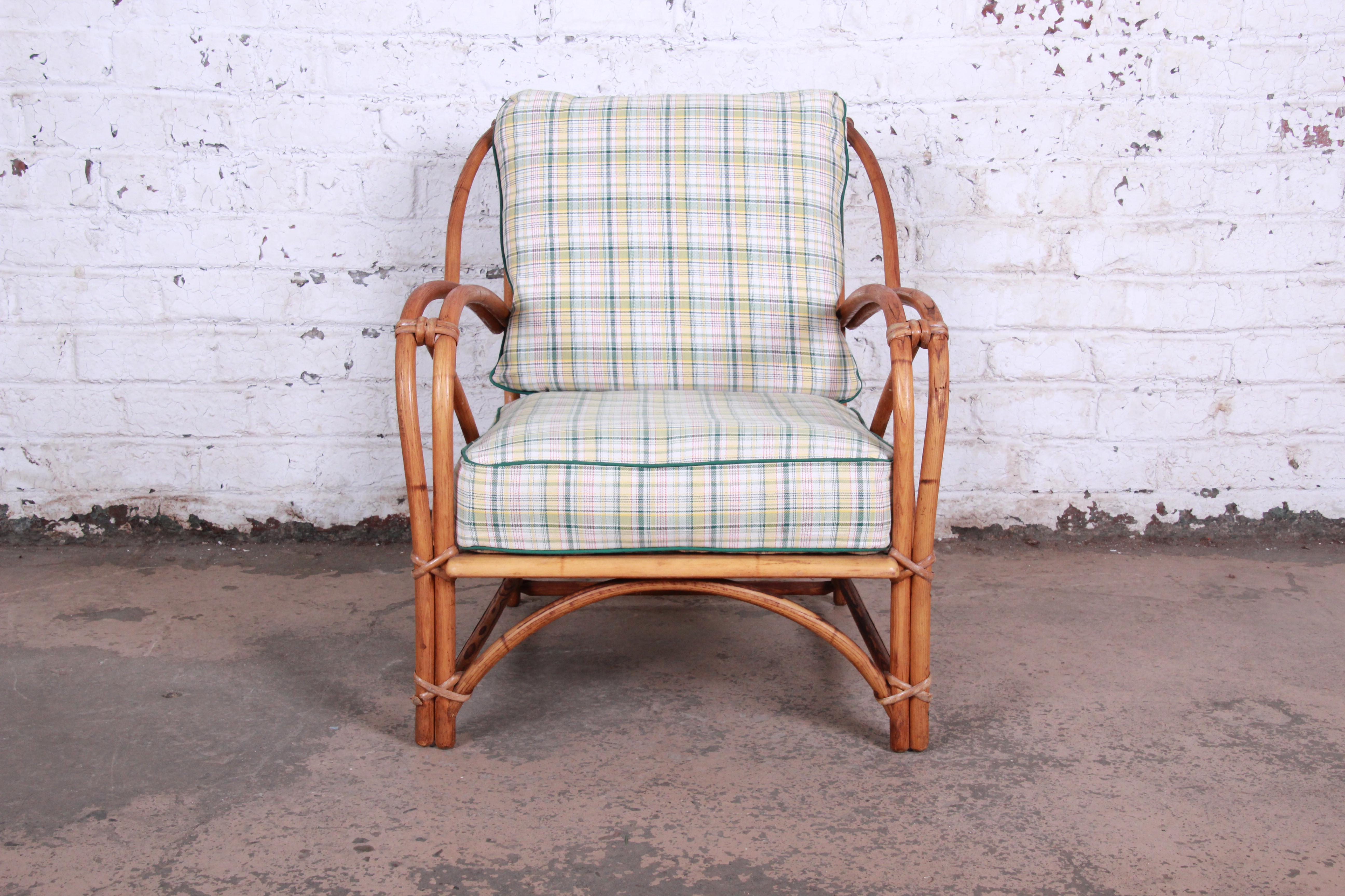A beautiful Mid-Century Modern Hollywood Regency lounge chair from the Ashcraft line by Heywood-Wakefield. The chair features a gorgeous bent rattan frame, and the original plaid upholstery in green, red, yellow, and white. The frame has clean