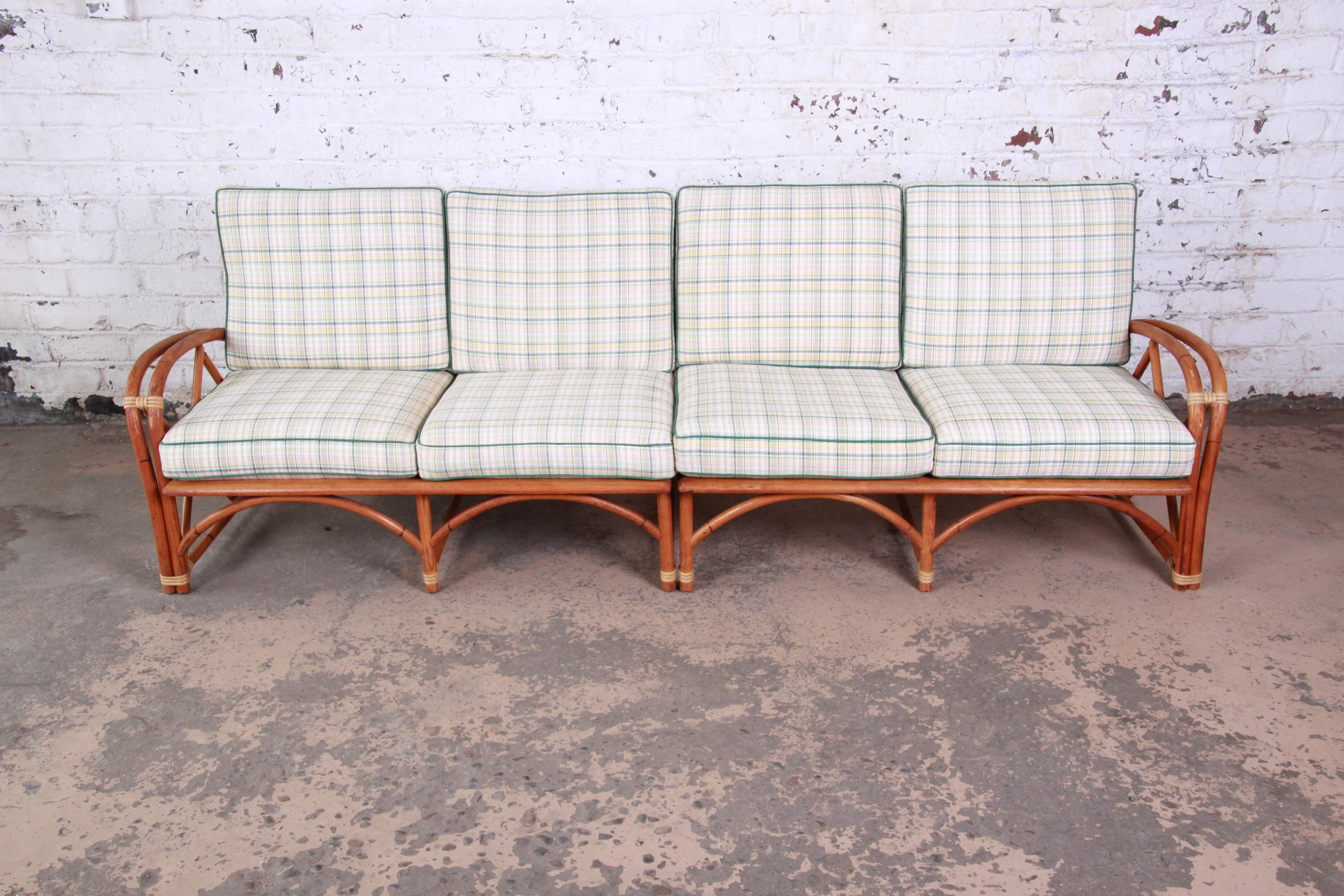 A nice and unique Mid-Century Modern Hollywood Regency style sofa from the Ashcraft line by Heywood-Wakefield. The sofa features a gorgeous bent rattan frame, and the original plaid upholstery in green, pink, yellow, and white. The frame has clean