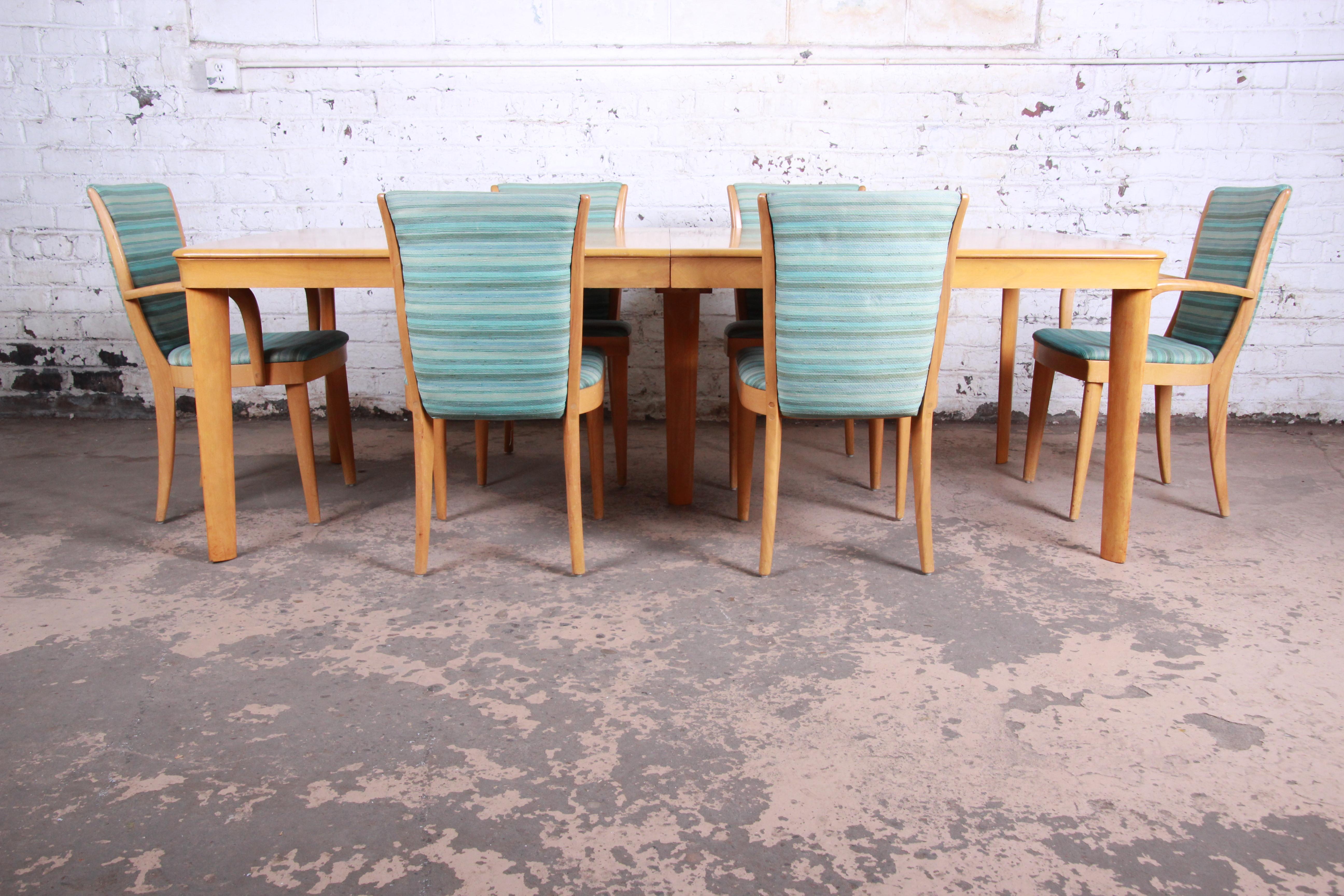 A gorgeous Mid-Century Modern dining set by Heywood Wakefield. The set includes the dining table with two leaves and six chairs. The table features solid maple construction with beautiful wood grain. It extends to seat large groups with two 15