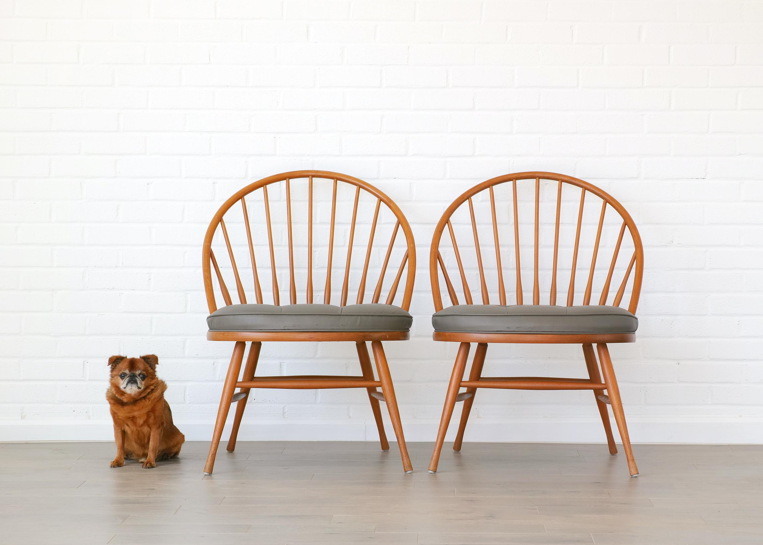For your consideration is this pair of Heywood Wakefield Windsor chairs featuring solid wood construction, original finish, gracefully bowed arch back, generously proportioned seat with gray vinyl tufted upholstery, and original Heywood Wakefield