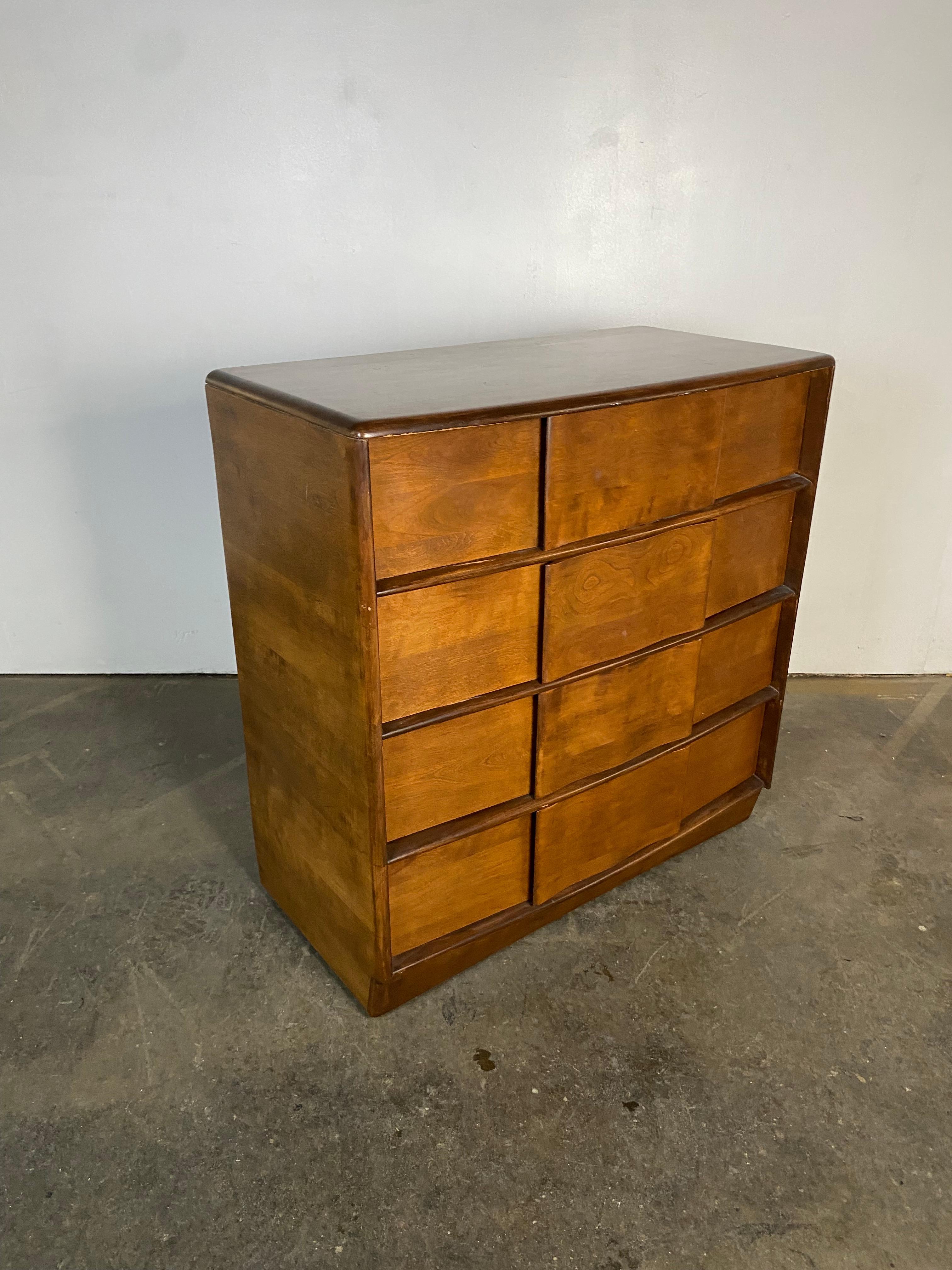 Heywood Wakefield four drawer dresser from the Sculptura line. This solid maple wood dresser has four spacious drawers with decorative sculpted concave handle pulls. Beautiful wood grain and color throughout. This dresser is on casters making it