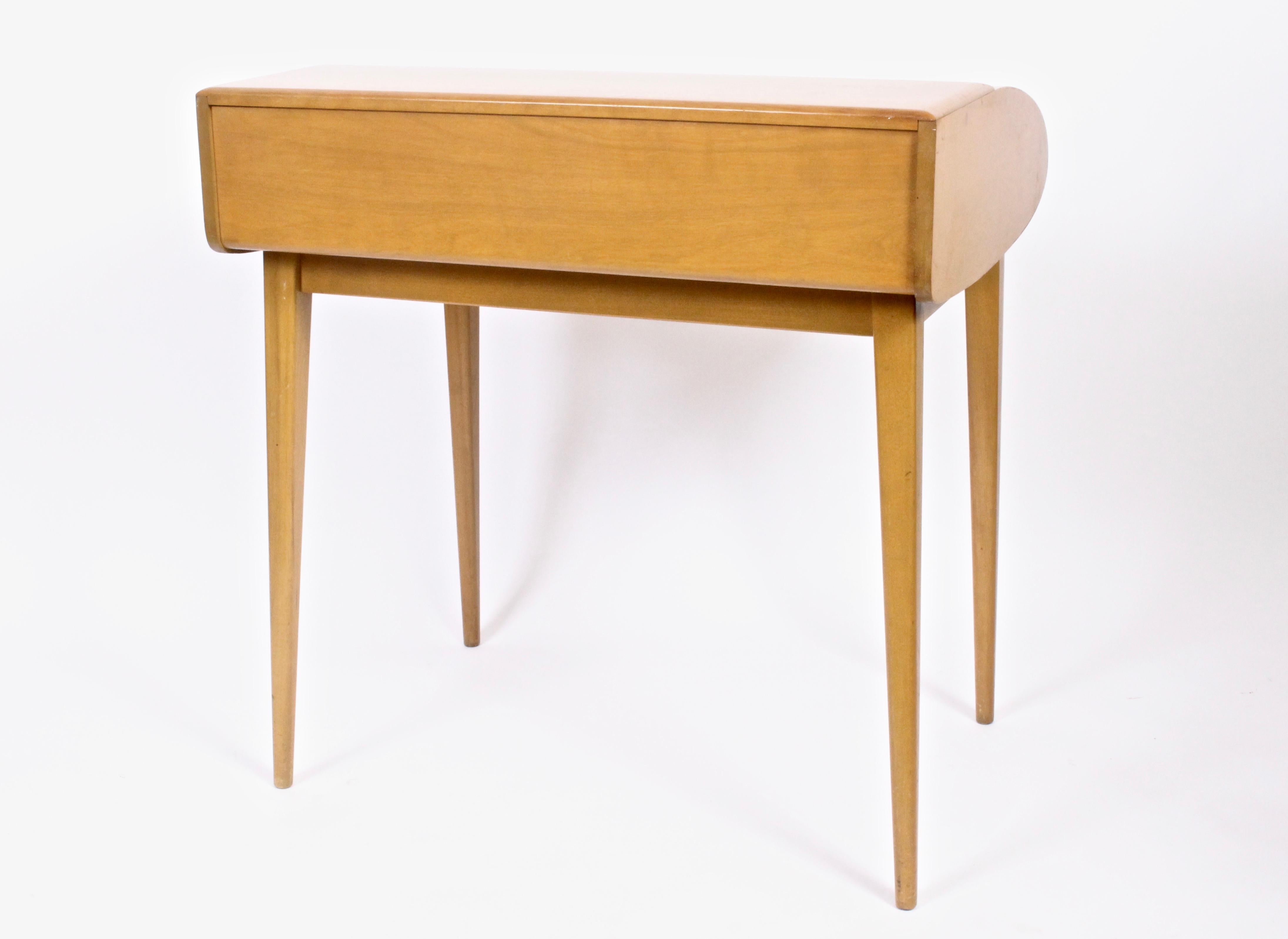 Classic American midcentury Heywood-Wakefield Petite Tambour Desk. With finished back. Featuring six interior compartments. Legs attach and detach with wingnuts. Amber finish. Rarity. Sleek. Storage. Small footprint. With Eagle burn stamp inside
