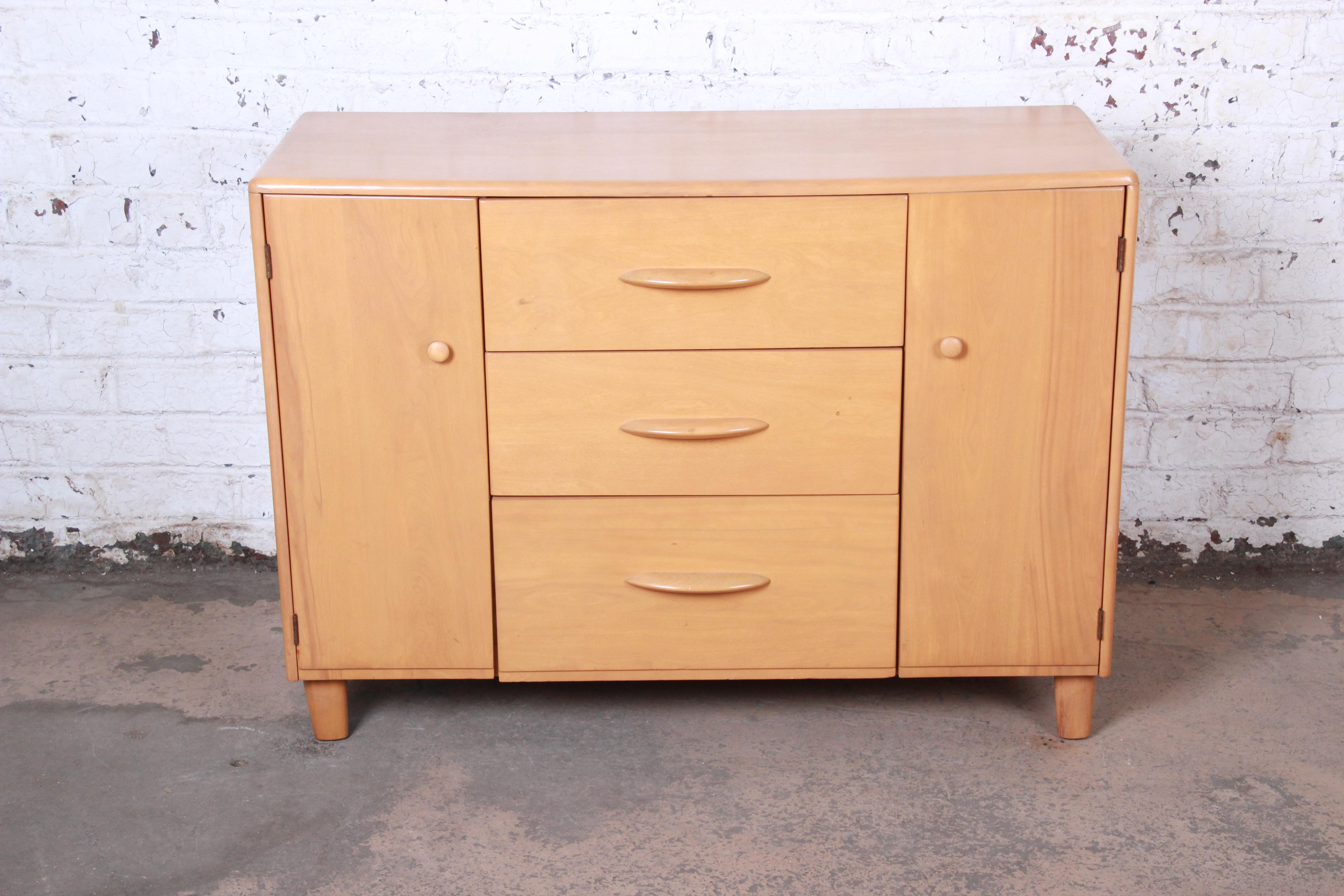A gorgeous Mid-Century Modern sideboard or credenza attributed to Heywood Wakefield. The credenza features solid maple construction with beautiful wood grain. It offers ample storage, with three deep drawers in the center and adjustable shelving