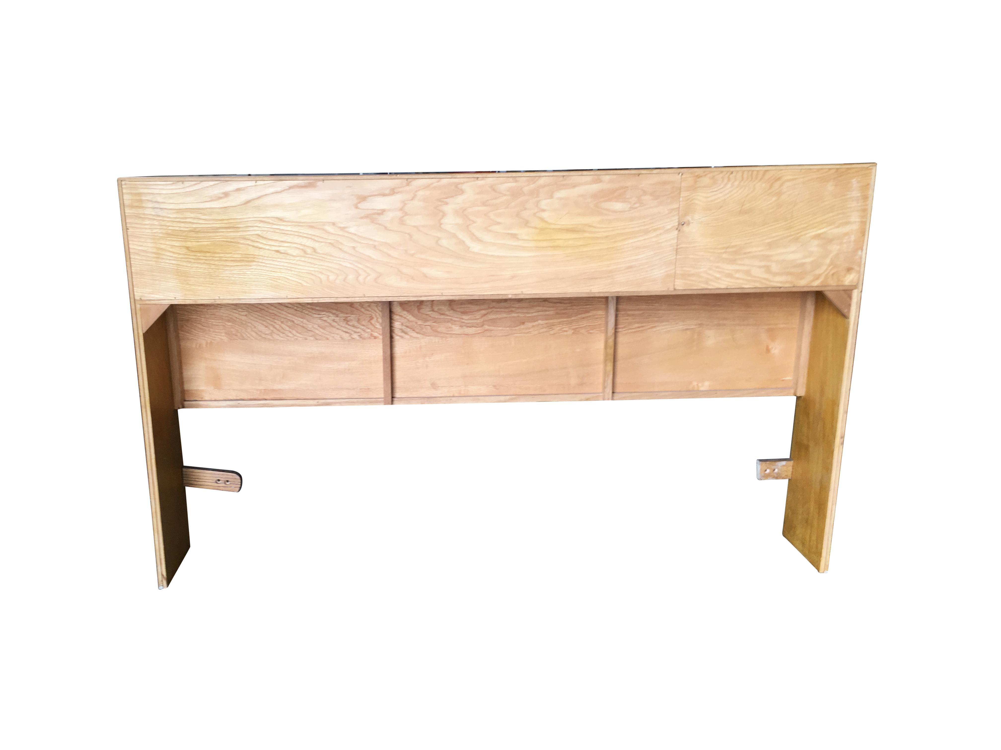 Midcentury era queen-size oak headboard in the manner of Heywood Wakefield. The headboard features three compartments and one sliding door. The top section doubles a shelf for extra storage decorating potential.