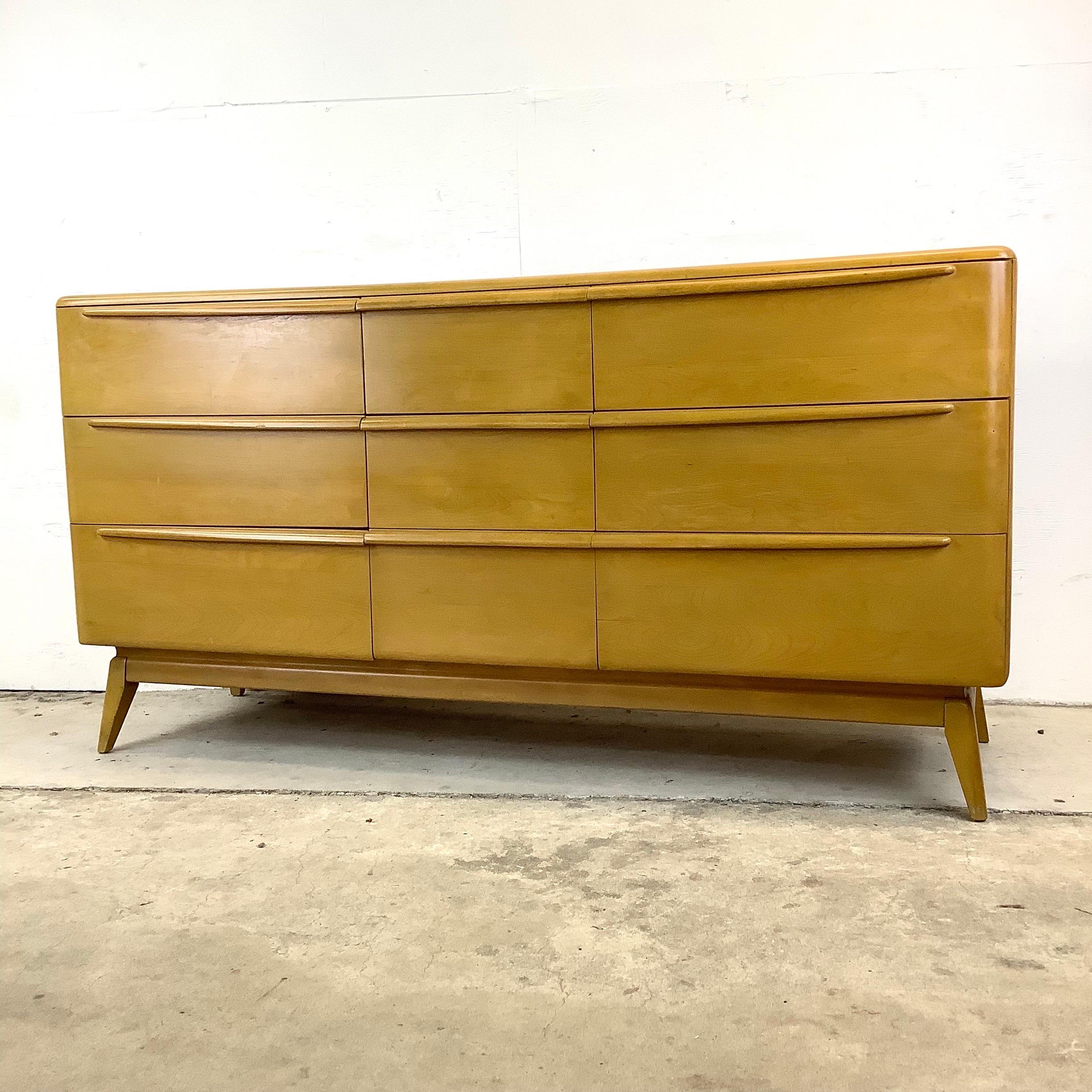This striking maple bedroom dresser from Heywood Wakefield features quality vintage craftsmanship and a spacious array of nine drawers for plenty of bedroom organization. The mid-century design of this piece evidences in its sleek  minimalistic