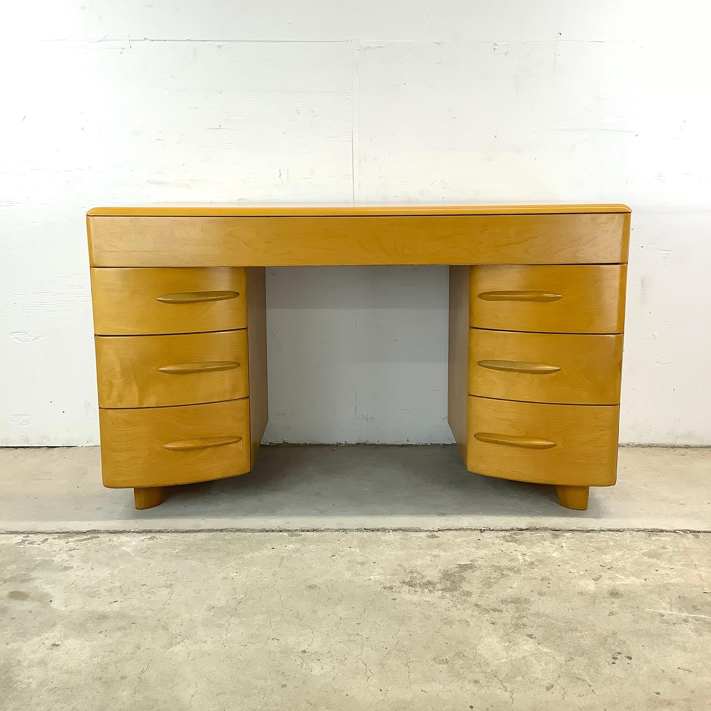 Invite mid-century charm into your workspace with this Heywood Wakefield Desk, a highly sought and highly functional icon of vintage modern furniture. This desk, with its sleek curves and warm honeyed finish, embodies the optimism and innovative