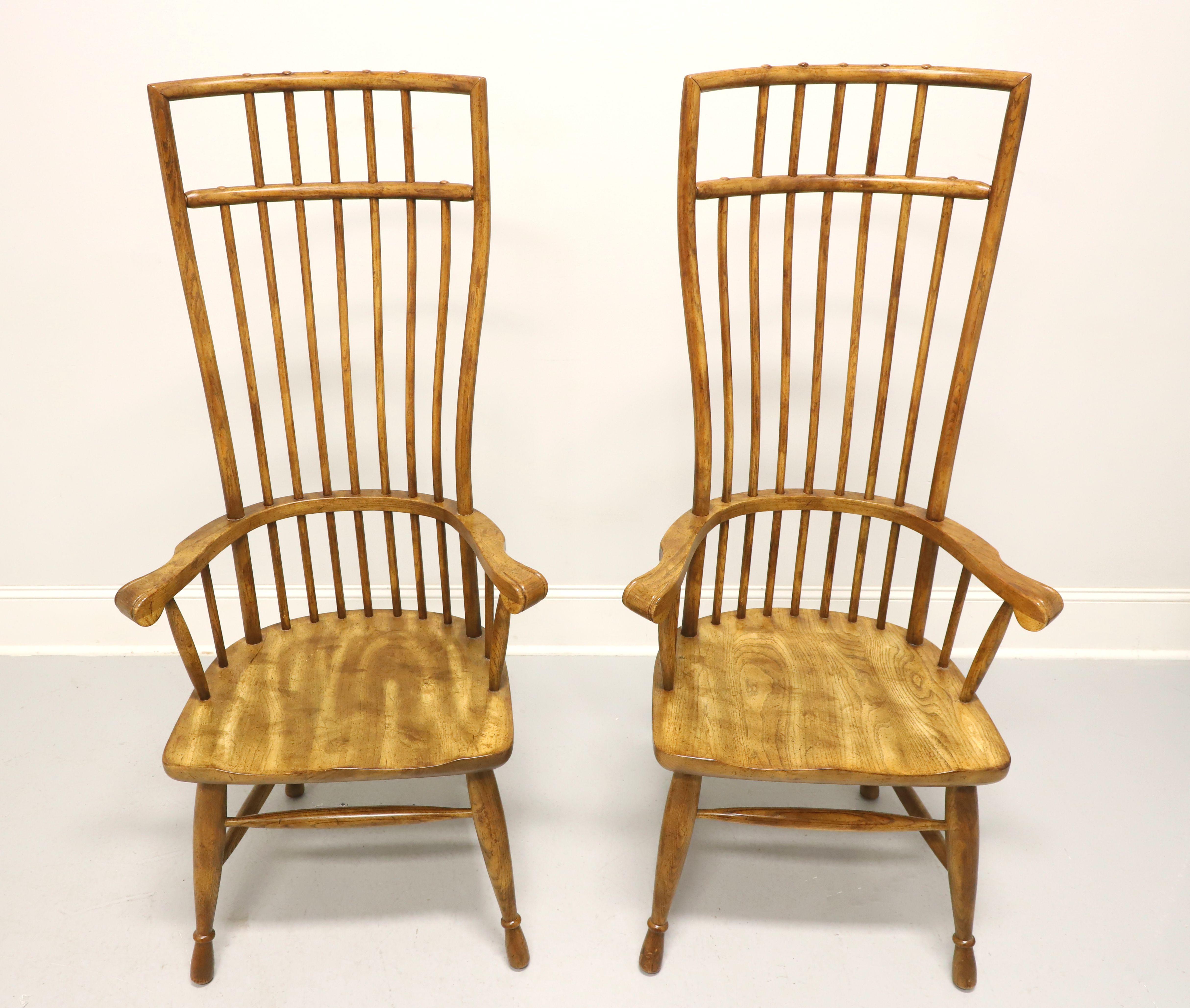 A pair of Mid 20th Century Windsor style armchairs by Hibriten. Solid oak with rounded crest rail, tall exaggerated backrest with curved spindles, curved arms with scroll ends, saddle shape seat, flared rounded legs and stretchers. Made in Lenoir,