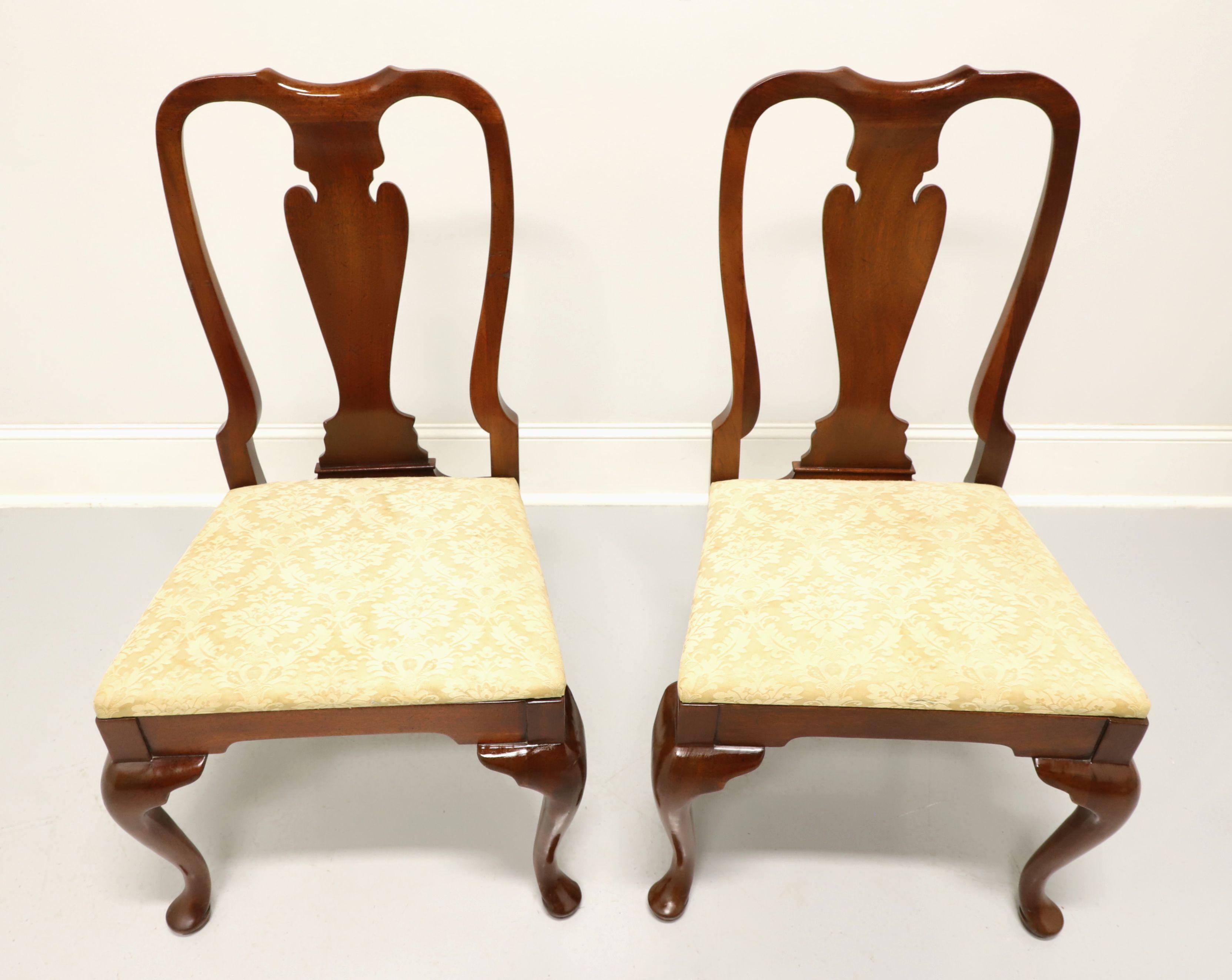 A pair of Queen Anne style dining side chairs by top quality furniture maker, Hickory Chair Company. Solid mahogany with their Amber Mahogany finish, carved back rest, creamy gold color brocade fabric upholstered seat, cabriole front legs and pad
