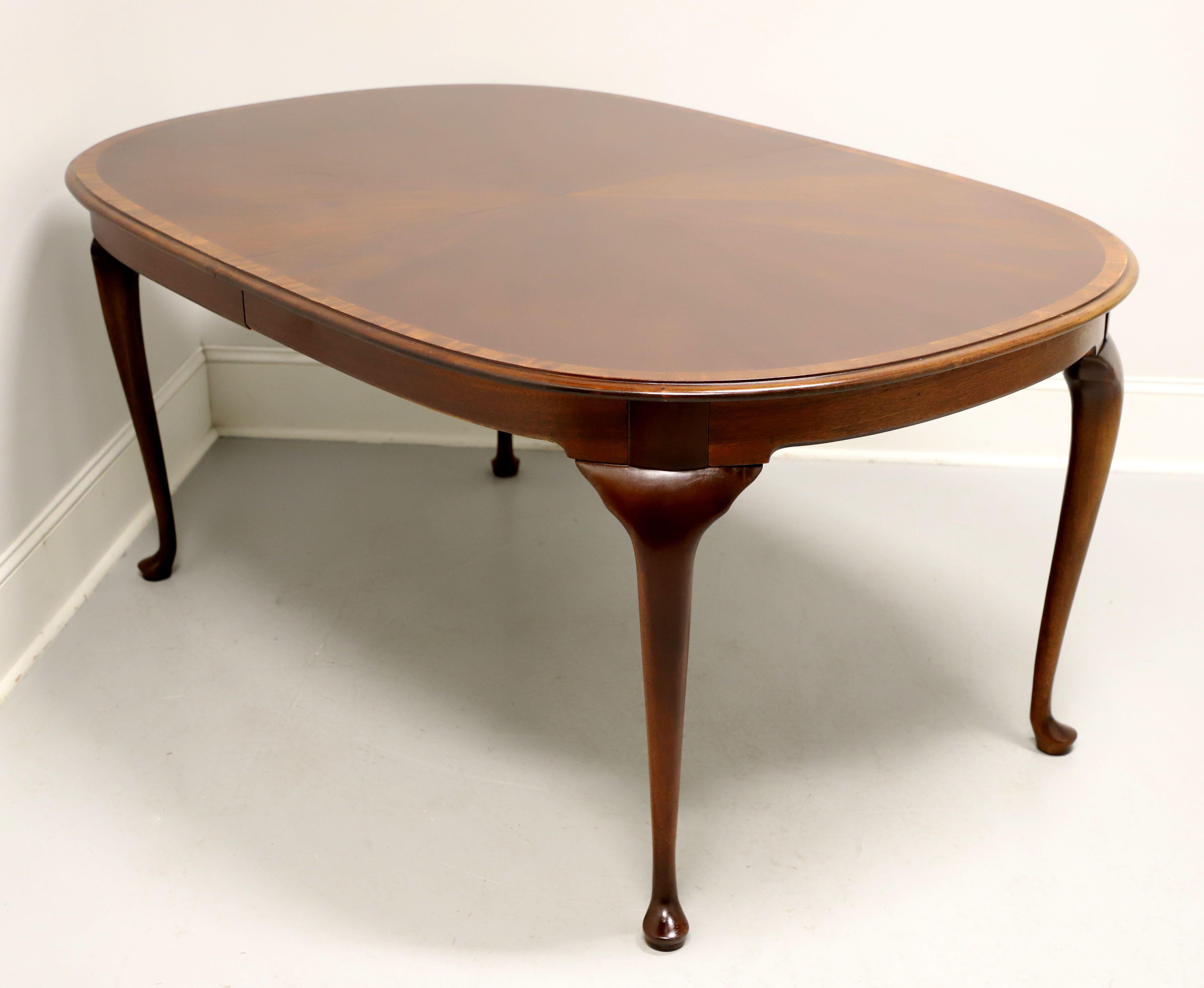 A Queen Anne style oval dining table by high-quality furniture maker Hickory Chair. Mahogany with a banded bevel edge to the top, solid apron, carved knees, cabriole legs and pad feet. Includes two 20 inch extension leaves for placement on metal