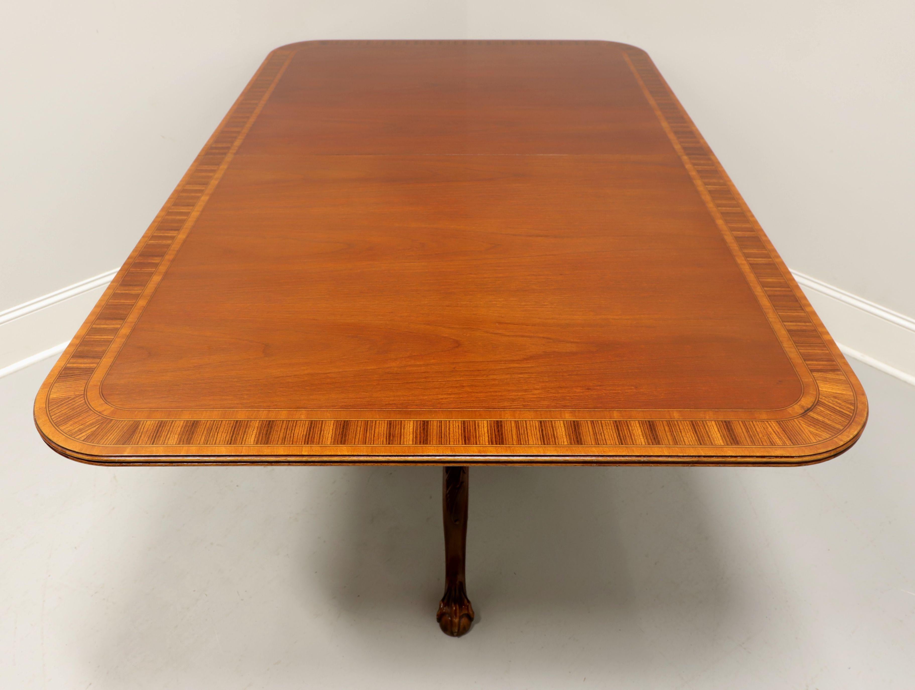 A Chippendale style double pedestal rectangular dining table by Hickory Chair. Mahogany with satinwood banding to top, ribbed edge, dual pedestals with three legs and ball in claw feet. Includes two extension leaves for placement on wood expansion
