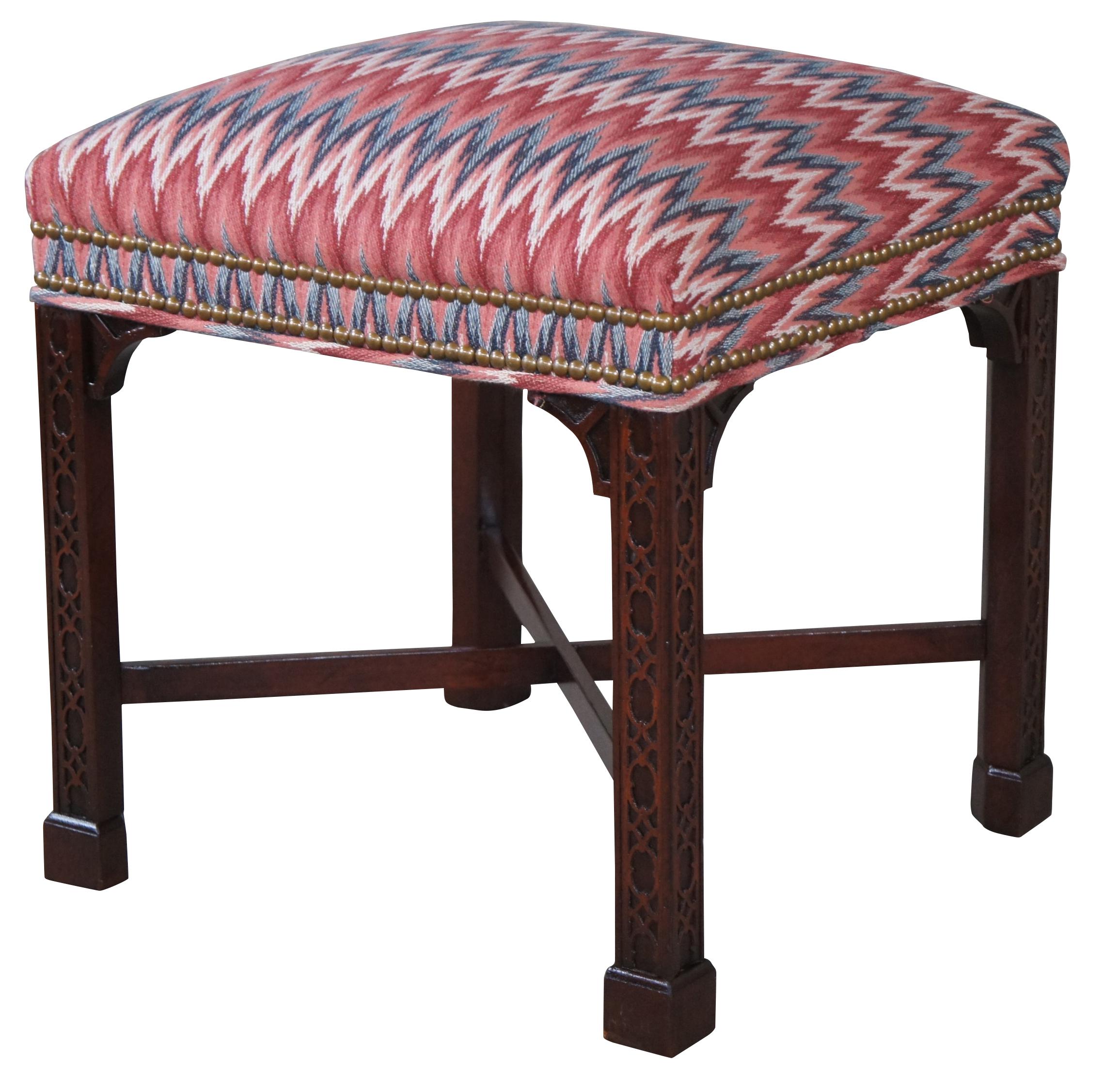Traditional Chinese Chippendale style ottoman or footstool by Hickory Chair, circa mid 20th century. A rectangular form made from solid mahogany with a chevron upholstered seat and brass nailhead trim. Features beautiful inset carved fretwork