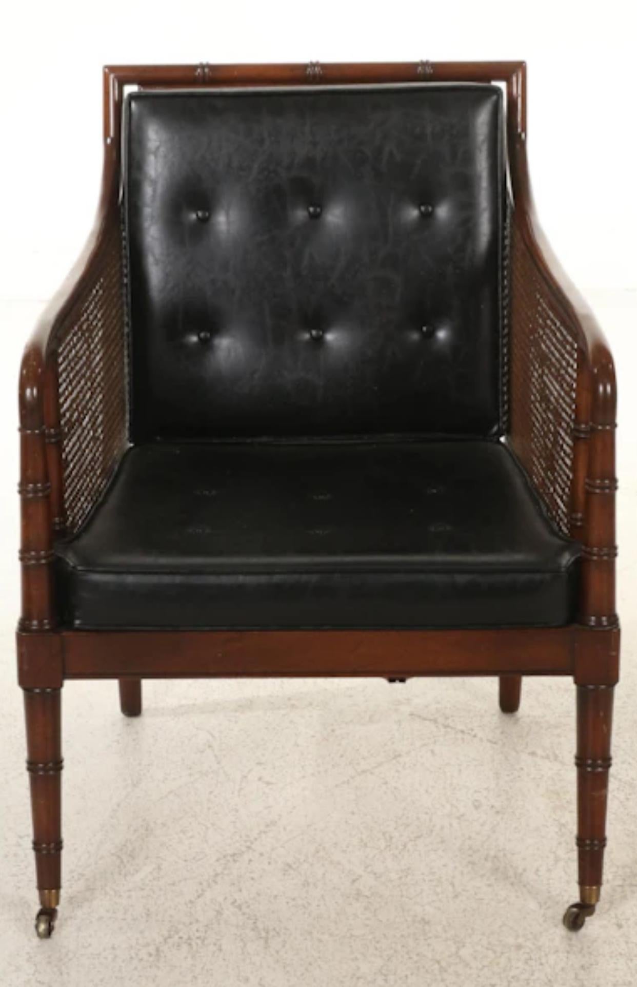 Hickory Chair Furniture Company  campaign style walnut regency faux bamboo  armchair and ottoman. Upholstered in black faux leather that has aged perfectly with minimal signs of wear. The cane back and sides are also in nicely aged appearance with