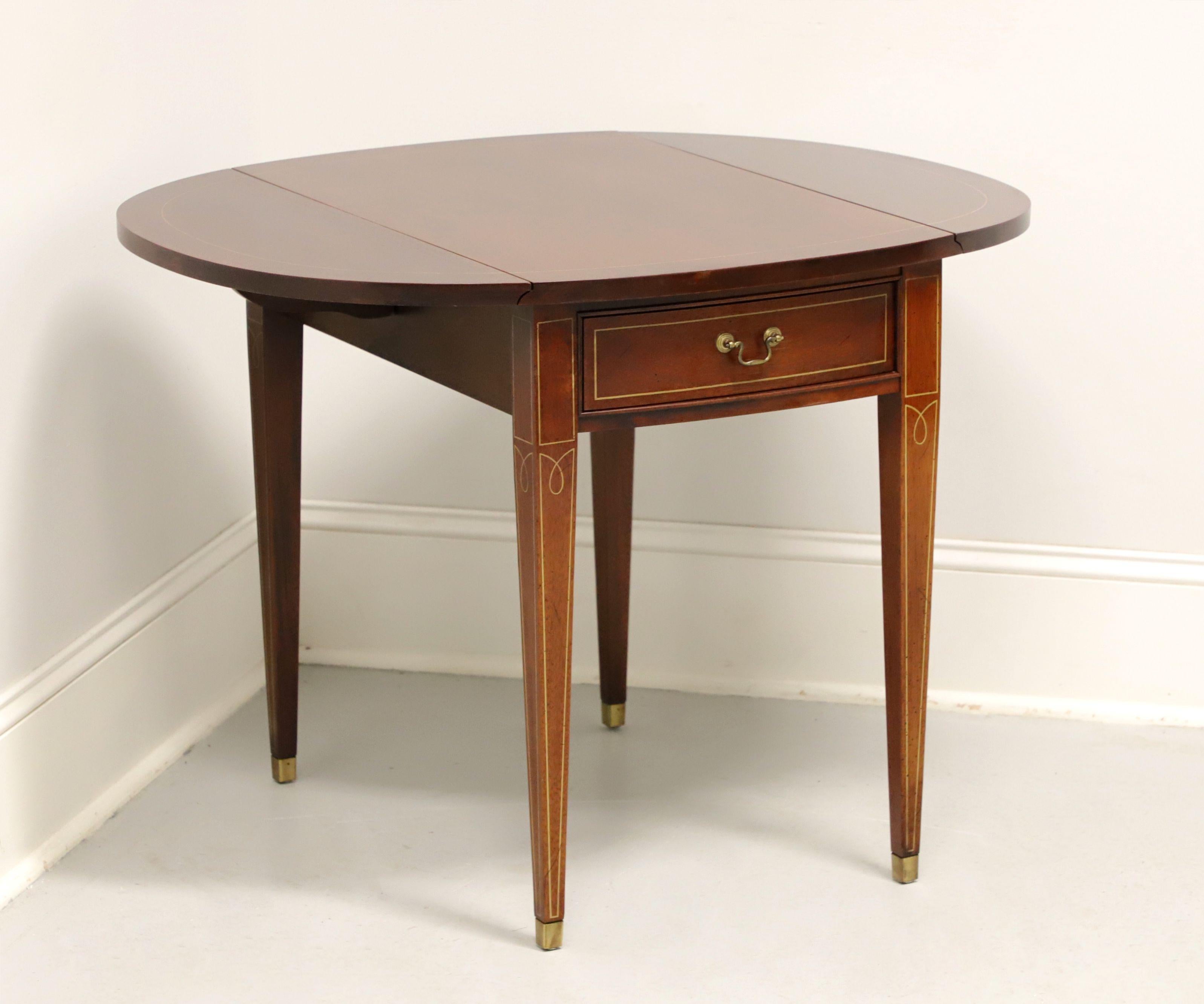 A Hepplewhite style Pembroke table by Hickory Chair, from their Historical James River Plantations Collection. Inlaid mahogany, inlaid string details, drop leaves, brass hardware, tapered straight legs, and brass toe caps. Features one drawer of