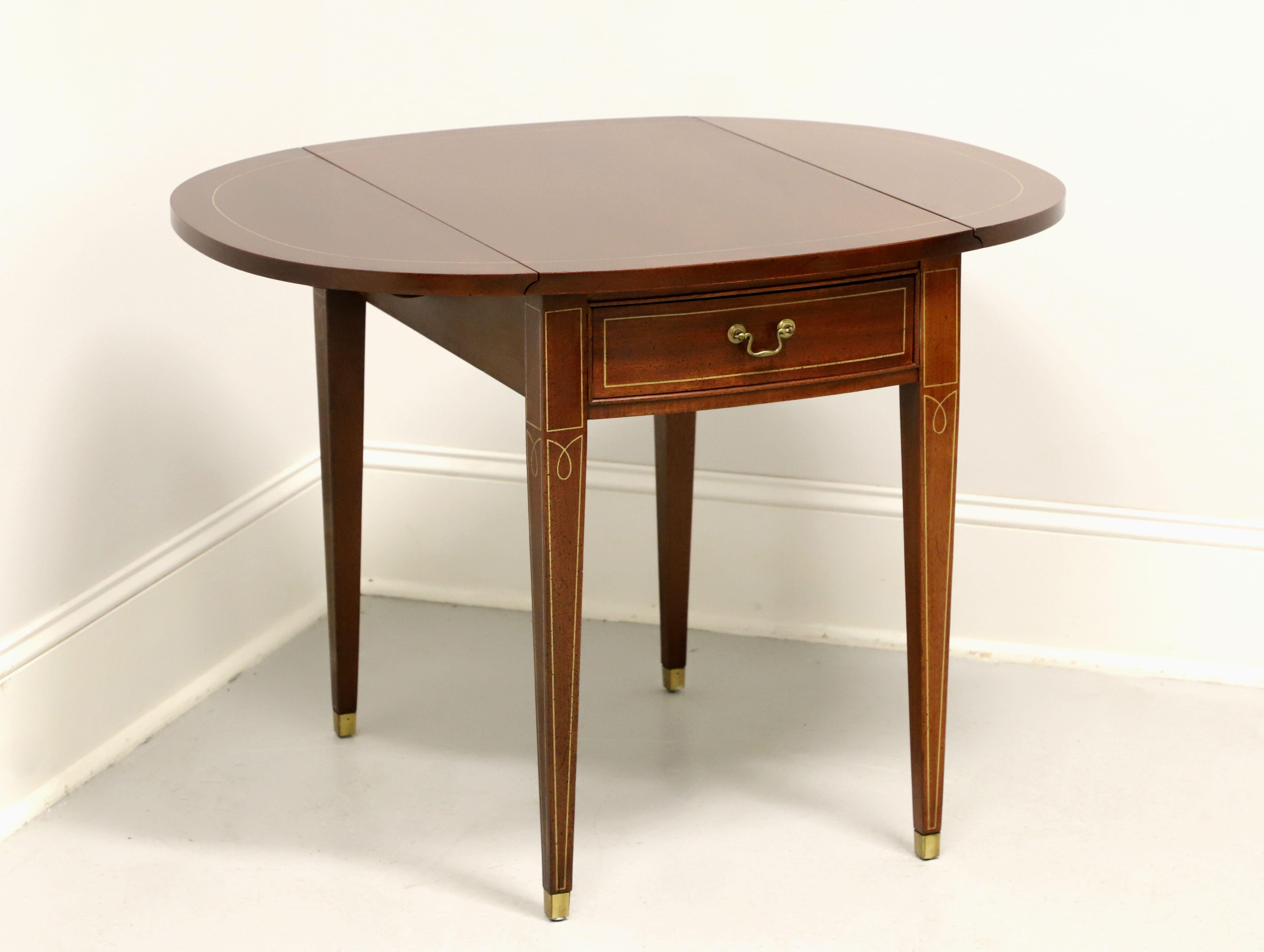 A Hepplewhite style Pembroke table by Hickory Chair, from their Historical James River Plantations Collection. Inlaid mahogany, inlaid string details, drop leaves, brass hardware, tapered straight legs, and brass toe caps. Features one drawer of