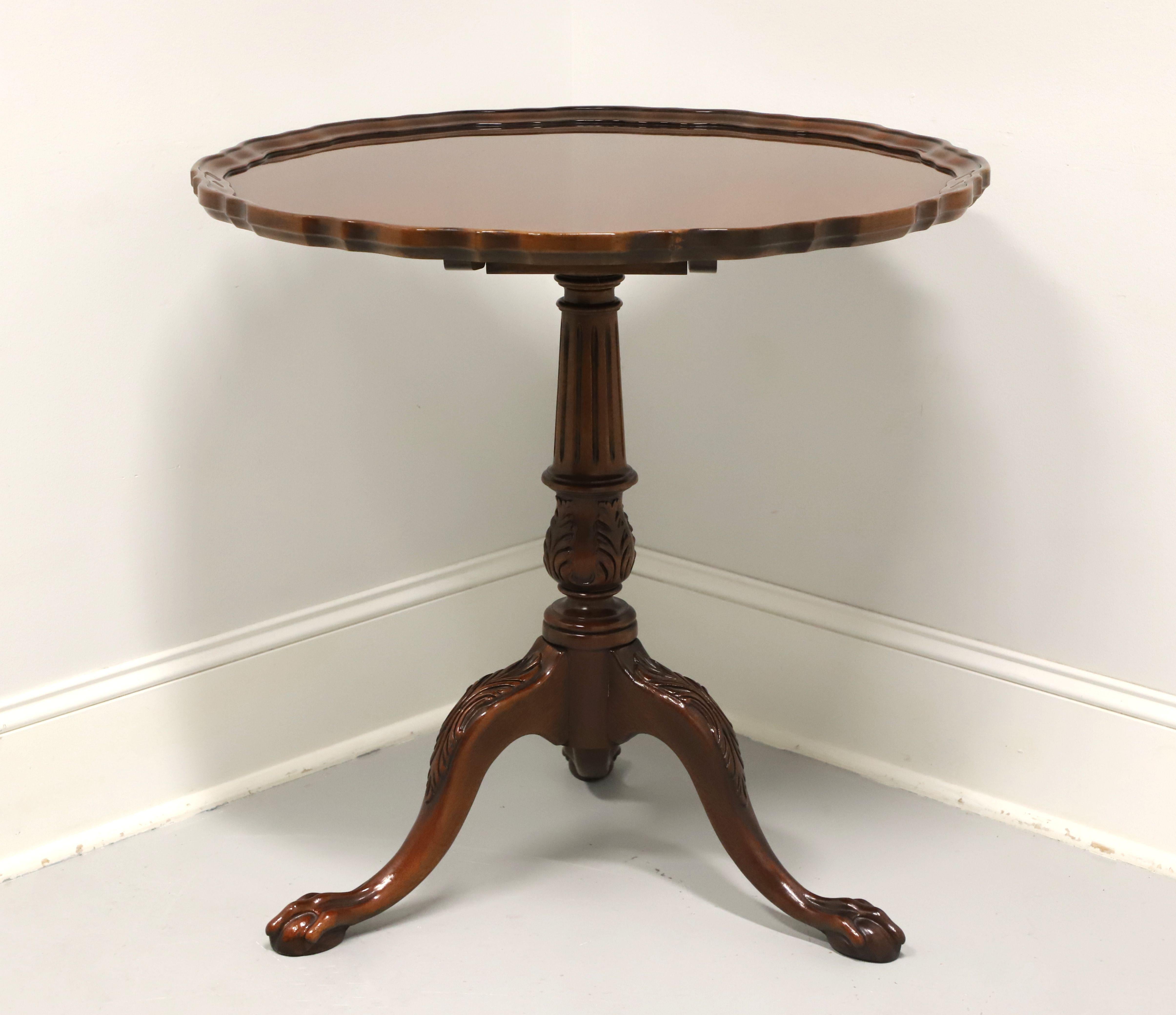 A Chippendale style tilt-top pie crust table by Hickory Chair Company. Solid mahogany with scalloped edge top, tilt mechanism, brass latch, turned & fluted pedestal, three legs with acanthus leaf carved knees, and ball in claw feet. Made in North