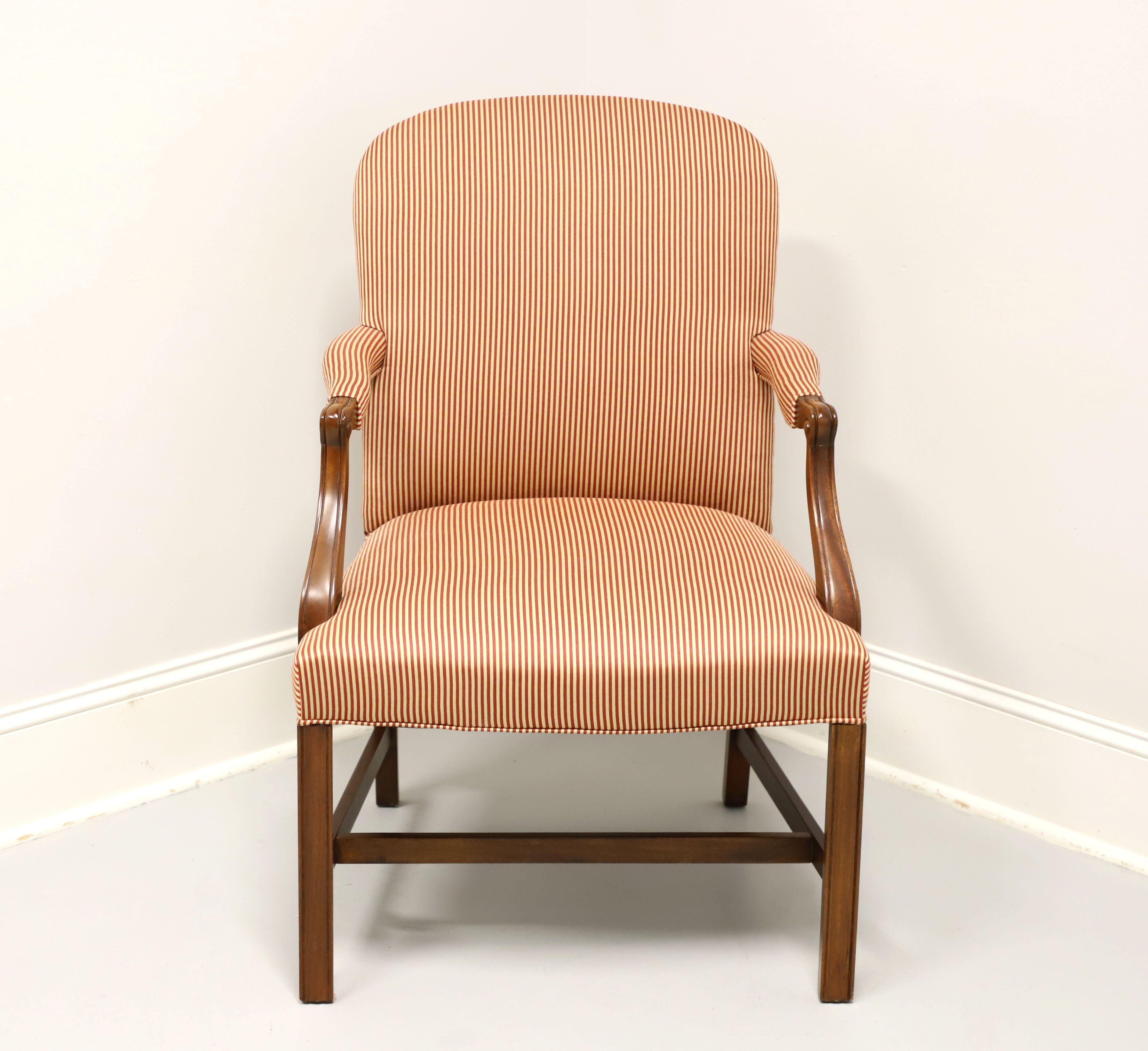 A Chippendale Martha Washington style upholstered armchair by Hickory Chair. Mahogany frame, red & cream color stripe pattern fabric upholstery, high back, upholstered arms with carved mahogany supports, carved straight front legs and stretcher
