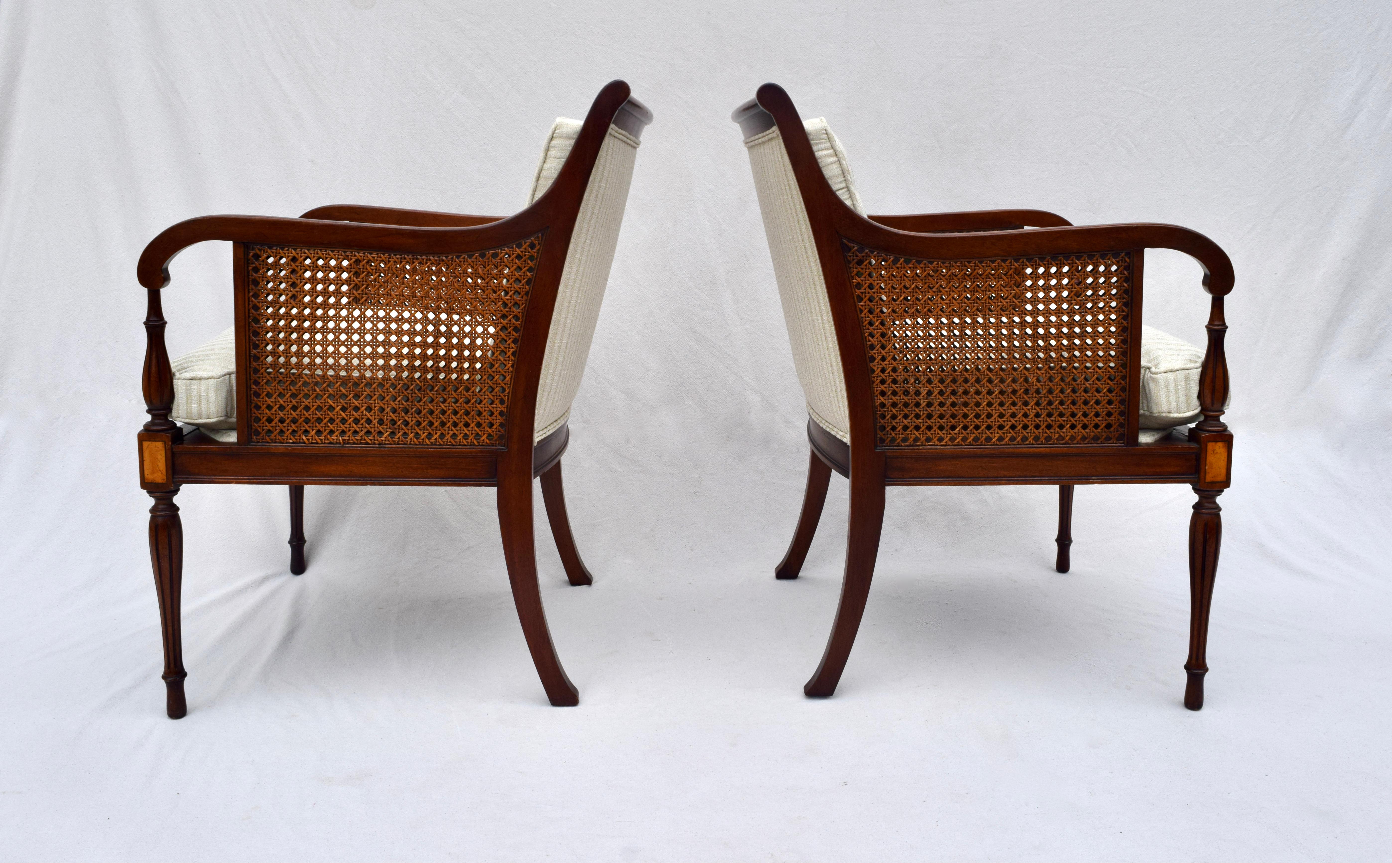 A pair of double caned, George III Regency style mahogany & satinwood armchairs with tapered reed & turned legs. Beautifully maintained, the pair is fully hand detailed, the caning being immaculate. New silk stripe upholstery includes button tufted