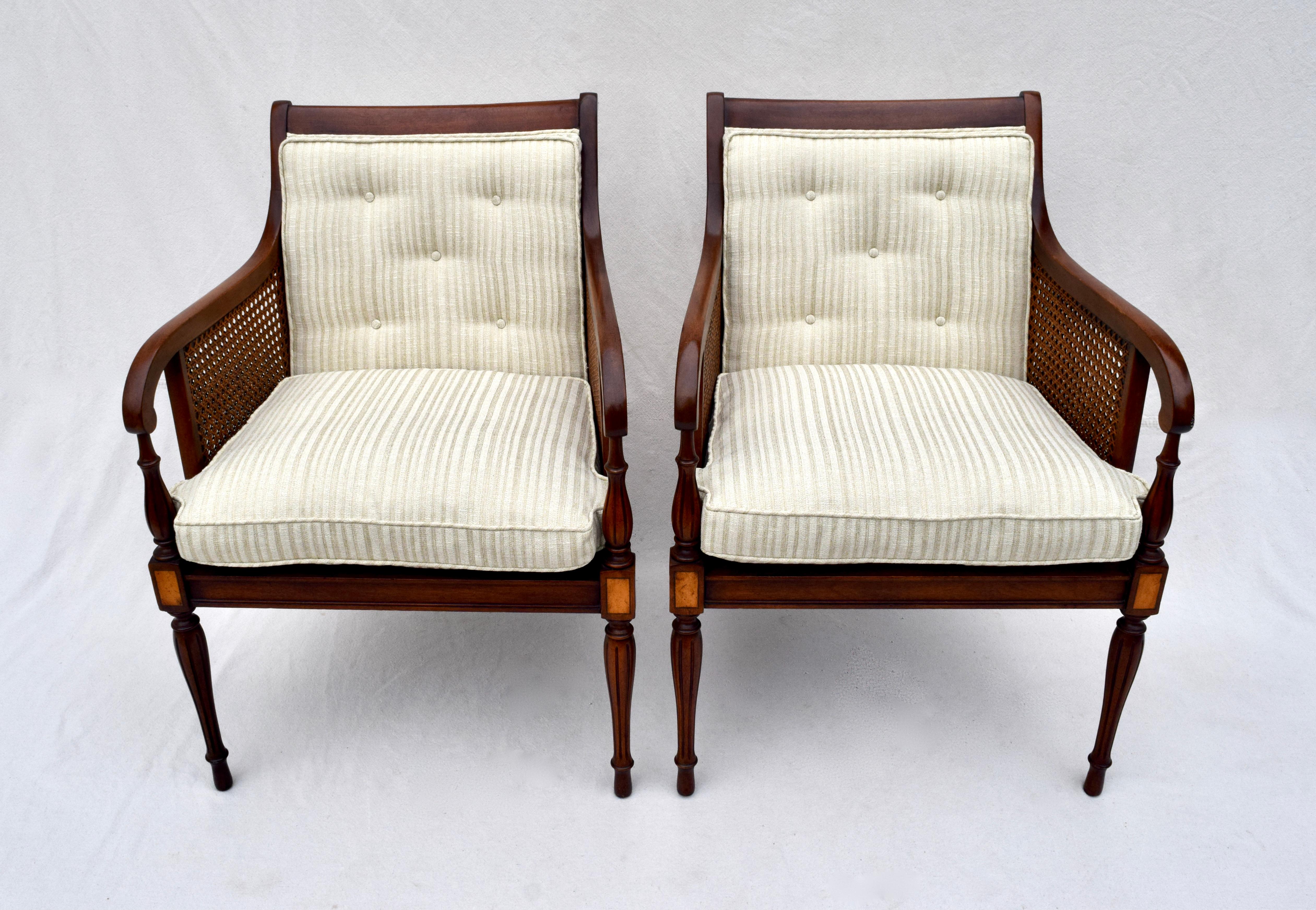 A pair of double caned, George III Regency style mahogany & satinwood armchairs with tapered reed & turned legs. The pair is fully hand detailed with beautifully maintained caning well in tact.. New silk stripe upholstery includes button tufted back