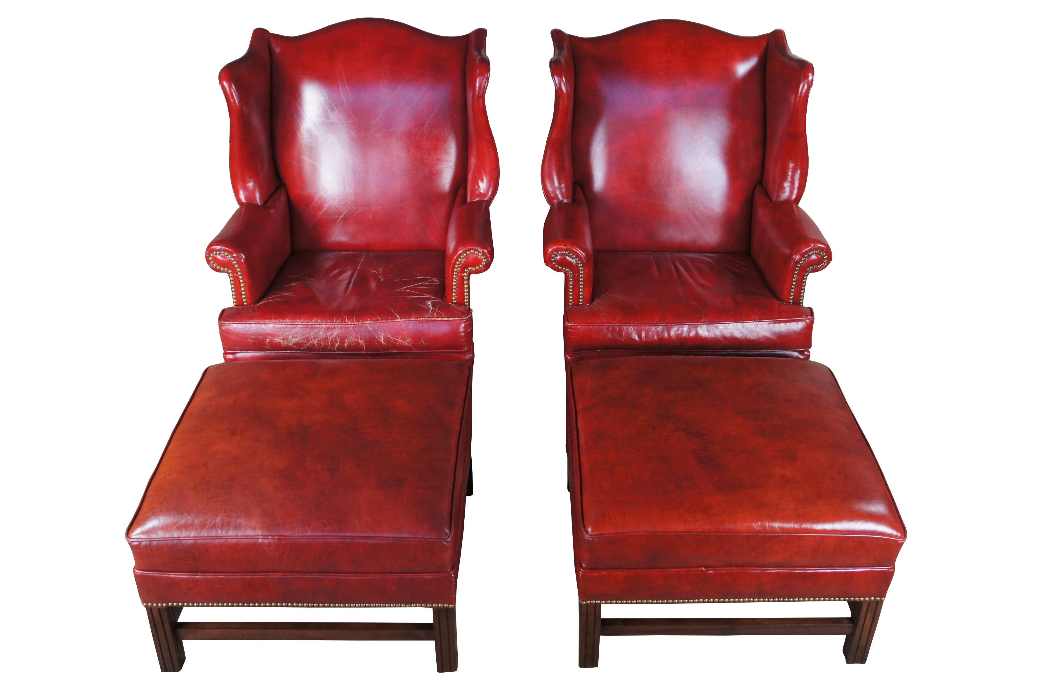 Mid century Hickory Chair Company wingback armchairs and ottomans.  Made of red leather featuring Chippendale styling with serpentine form, nailhead trim, rolled arms and fluted mahogany legs.

Dimensions:
33