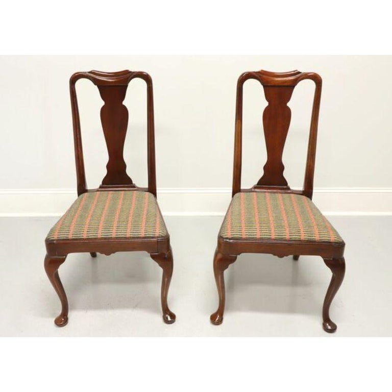 A pair of Queen Anne style dining side chairs by top quality furniture maker Hickory Chair Company. Solid mahogany with carved backs, blue-salmon-gold patterned fabric upholstered seats, cabriole legs and pad feet. Made in North Carolina, USA, in