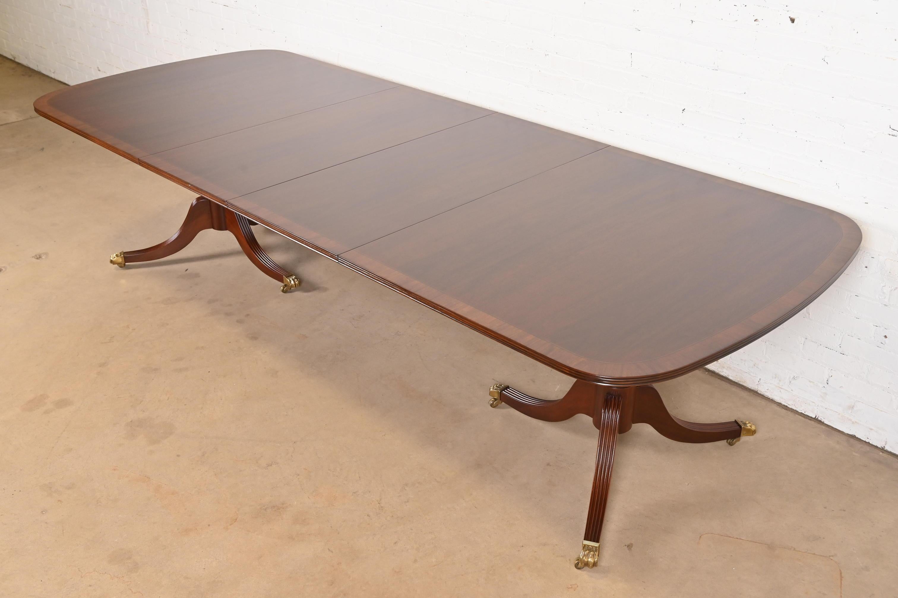 An exceptional Georgian, Chippendale, or Regency style double pedestal extension dining table

By Hickory White 

USA, Circa 1980s

Gorgeous book-matched mahogany, with satinwood banding, carved solid mahogany pedestals, and brass paw feet on brass