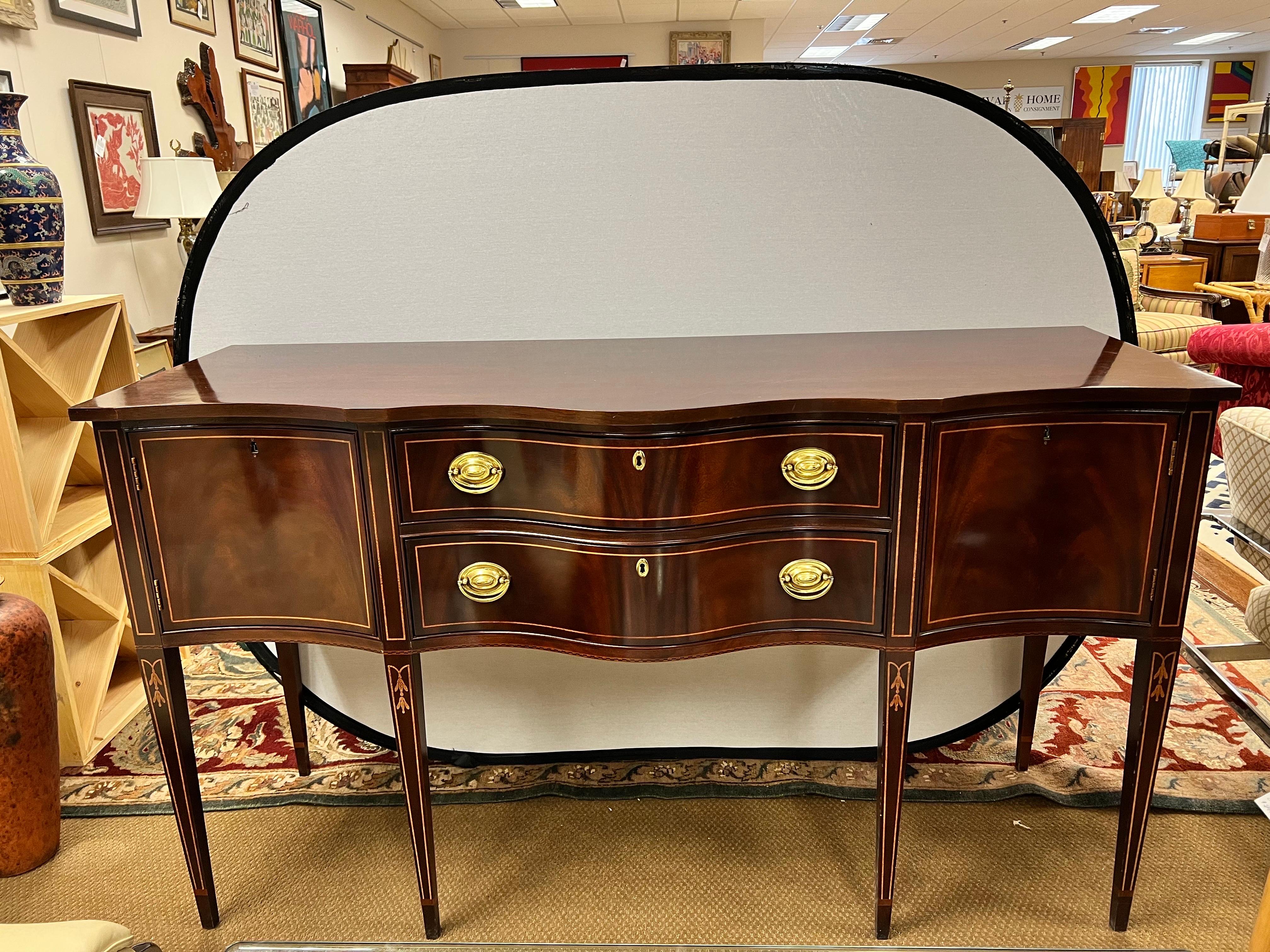 Classic mahogany sideboard/buffet that boasts two high quality dovetailed drawers flanked by two doors on each side. The piece rests on six square tapered legs with inlay. Also features felt lined drawer for your silver. Comes complete with keys.