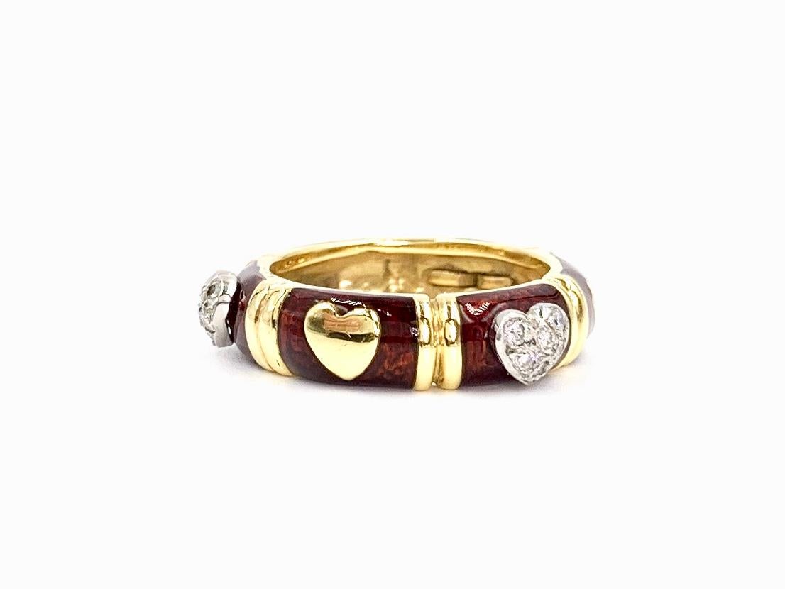 A 5mm wide 18 karat yellow gold heart motif ring featuring diamonds and deep red enamel by Hidalgo. Handmade in Italy, Hidalgo expertly crafts stackable rings with hand painted enamel. Three diamond hearts have a total weight of .36 carats at