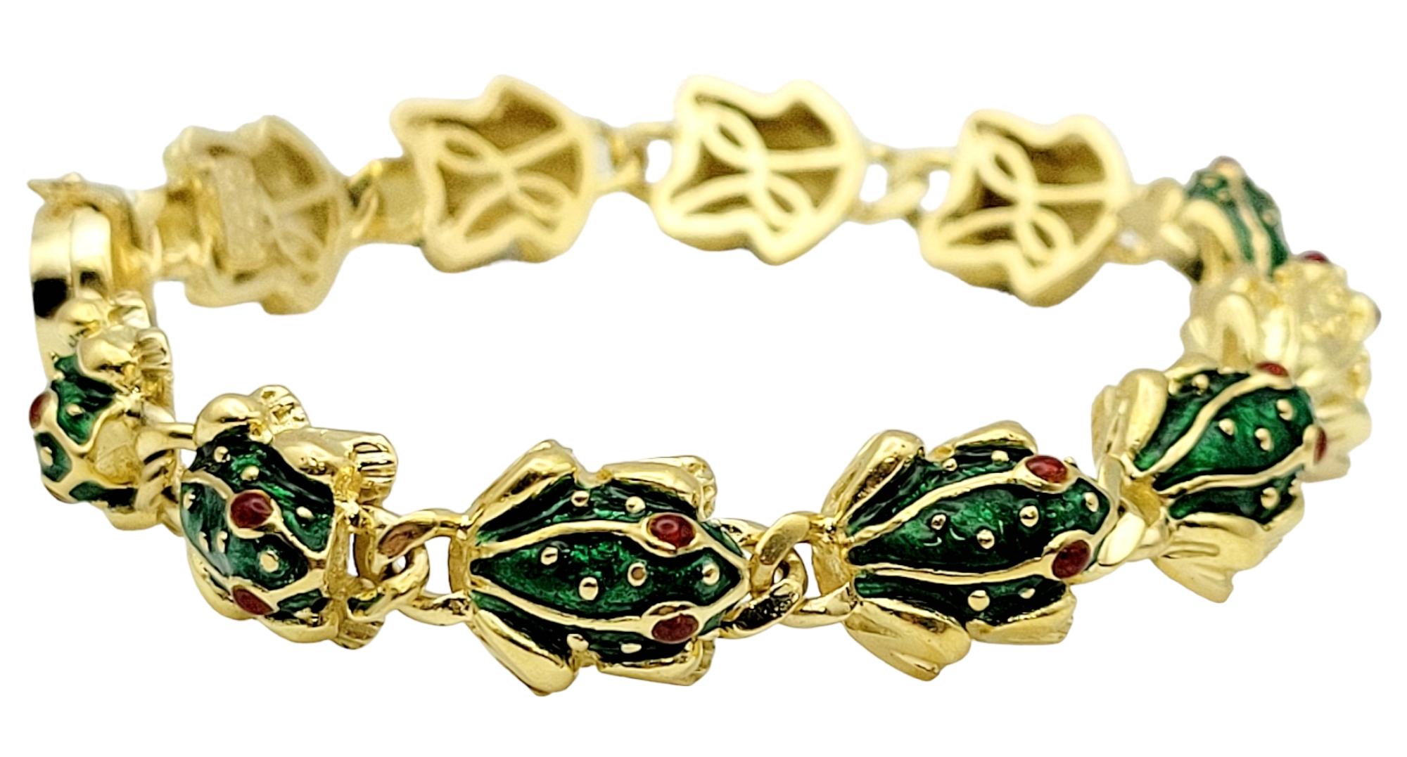 This incredible, modern gold frog link bracelet is an authentic Hidalgo design! The beautiful bracelet features detailed 3-D frog links with green and red enamel accents. There are 11 frog links, 10 of which feature a green enamel body with red