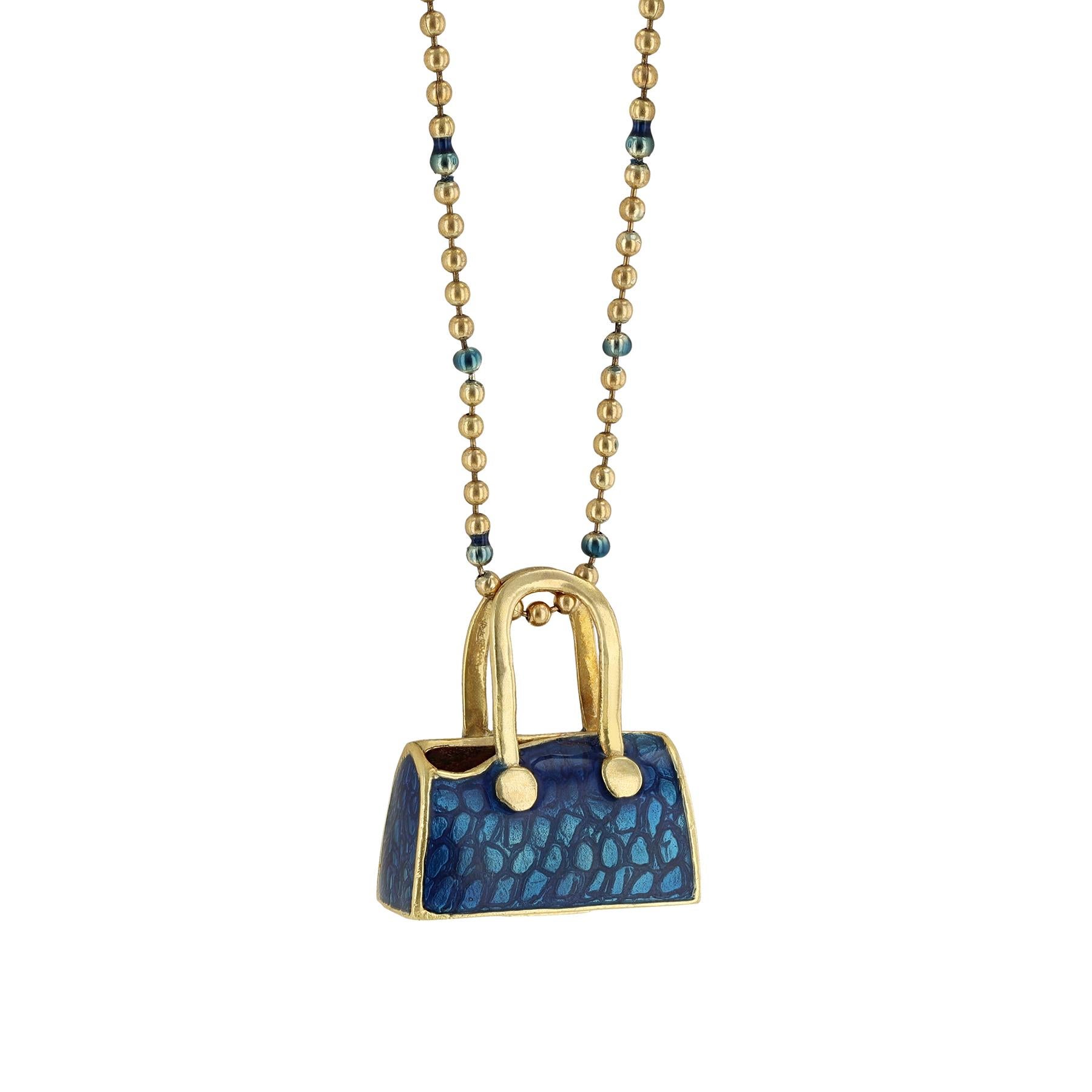 Ce collier est réalisé en or jaune 18K et en émail bleu. Il comporte un pendentif en forme de sac à main.