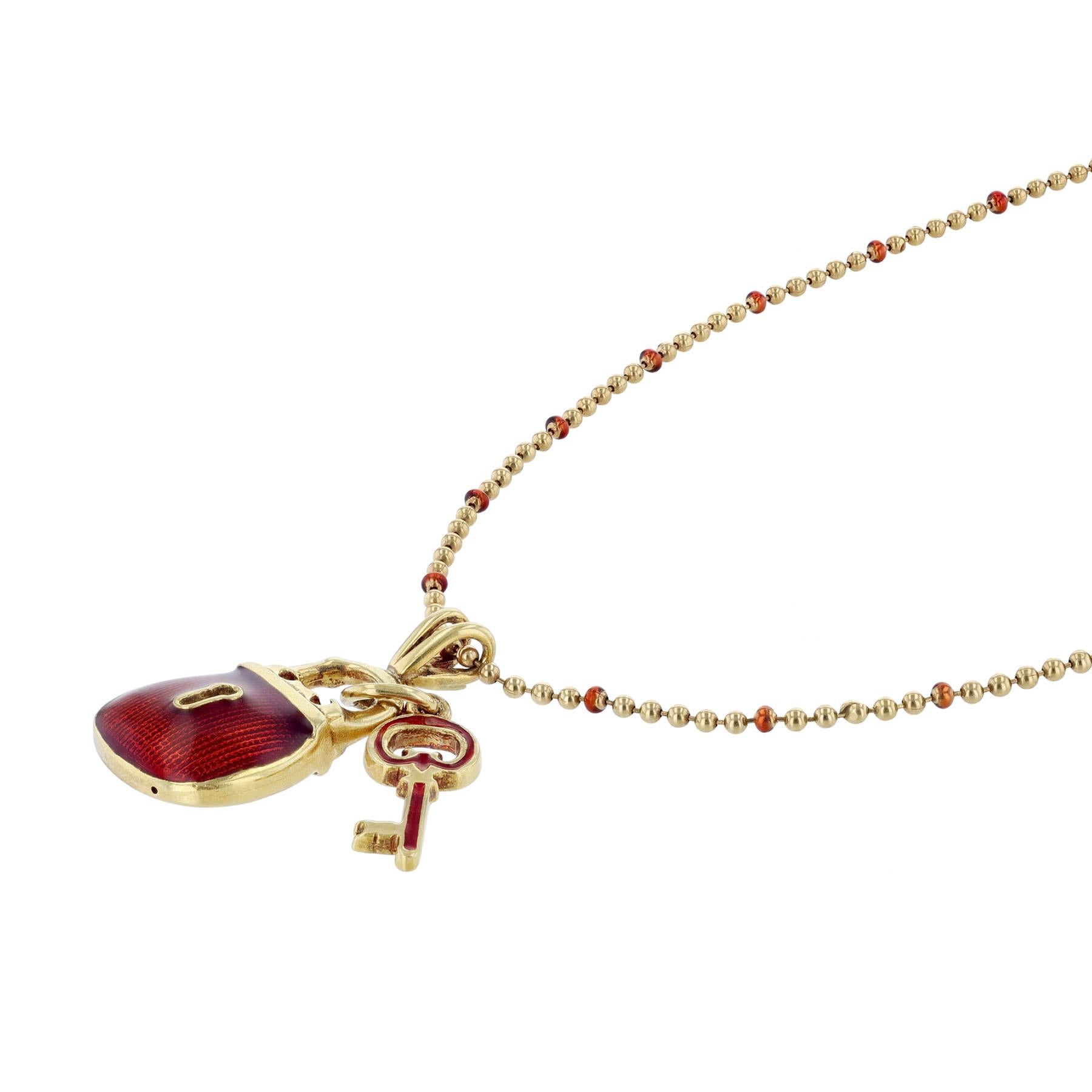 This necklace is made in 18K yellow gold and red enamel. It features a lock and key pendant pendants.
