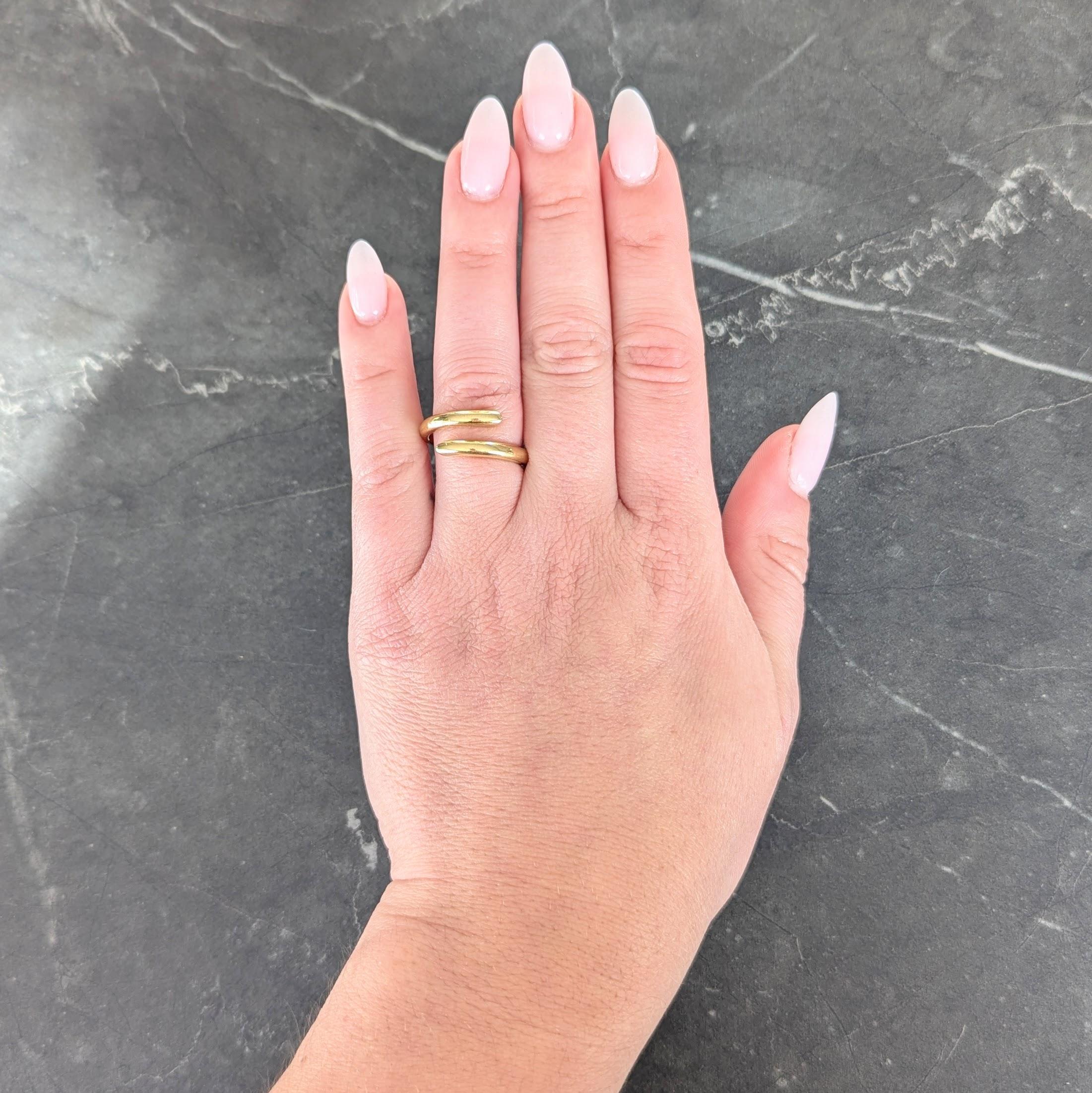 Designed as a rounded yellow gold band
With open bypass-style terminals
Complete by high polish finish
Stamped for 18 karat gold
Fully signed for Hidalgo
Circa: 1990s
Ring Size: 6 1/2 and sizable
Measures north to south 10.0 mm and sits 2.5 mm