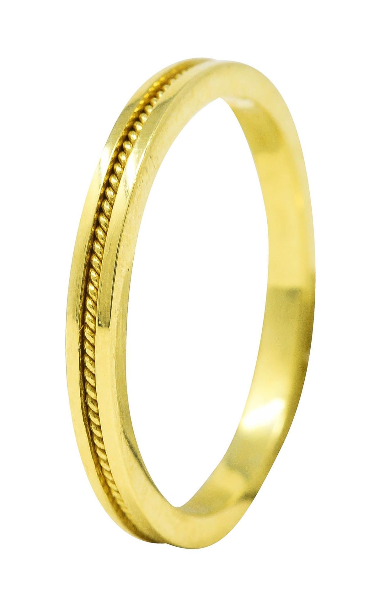 Band ring features a recessed channel with twisted rope motif fully around. With high polished gold surround. Stamped 750 for 18 karat gold. Signed with maker's mark for Hidalgo. Circa: 1990's. Ring size: 6 and not sizable. Measures: North to South