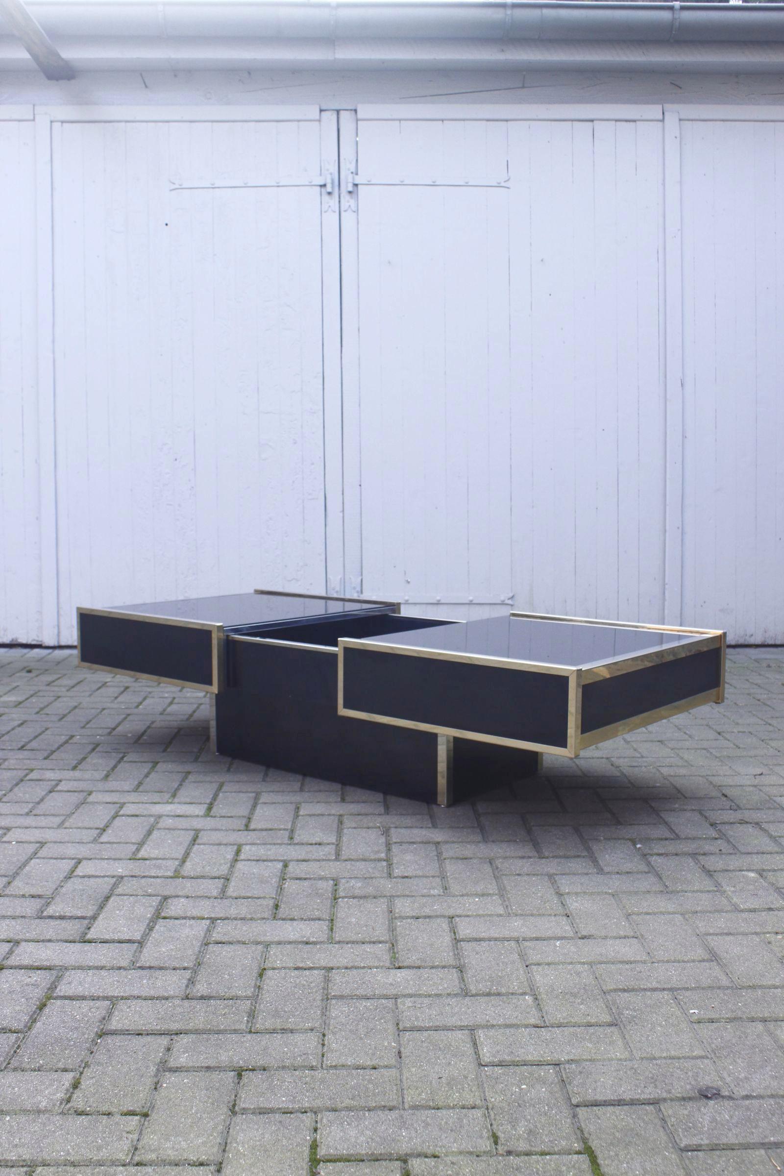 Beautiful coffee table with hidden bar by Maison Lancel Paris, circa 1970.

The frame is in gilded metal, the top in glass, the interior part for storing bottles and glasses is in chrome metal, the contours and base are in glossy black melamine