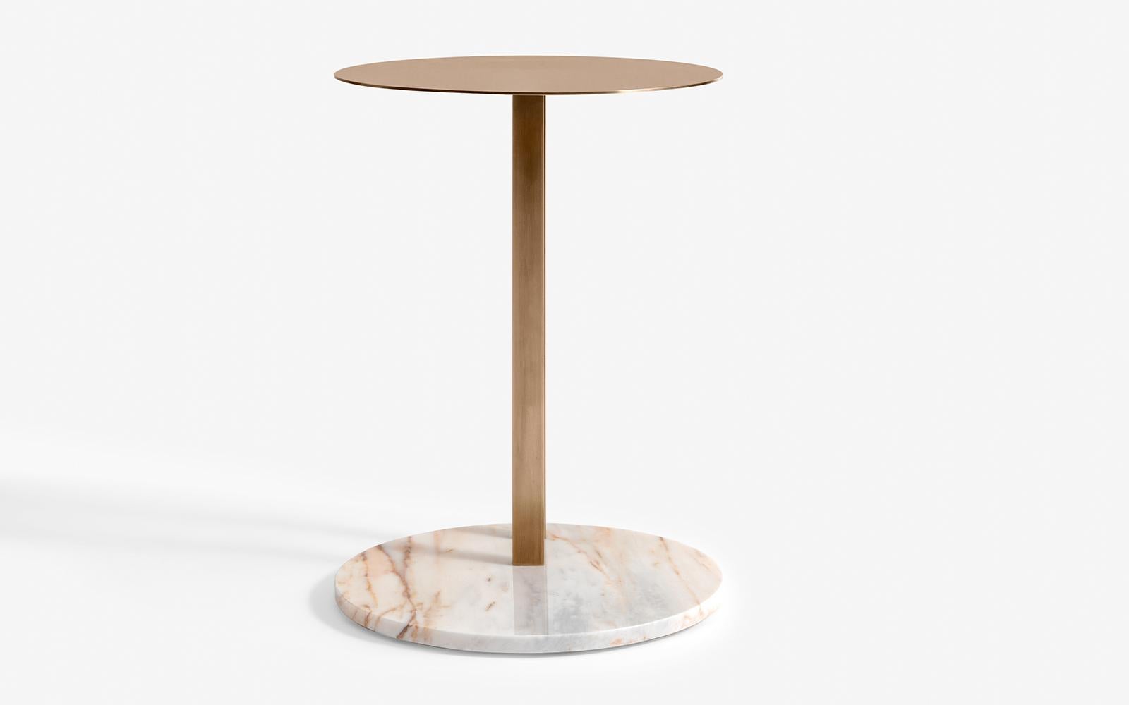 The Hidden C side table is a stunning piece of furniture designed with a marble base and a brass top that seamlessly intersect to create a flawless look. This side table is unique in that it features a hidden 