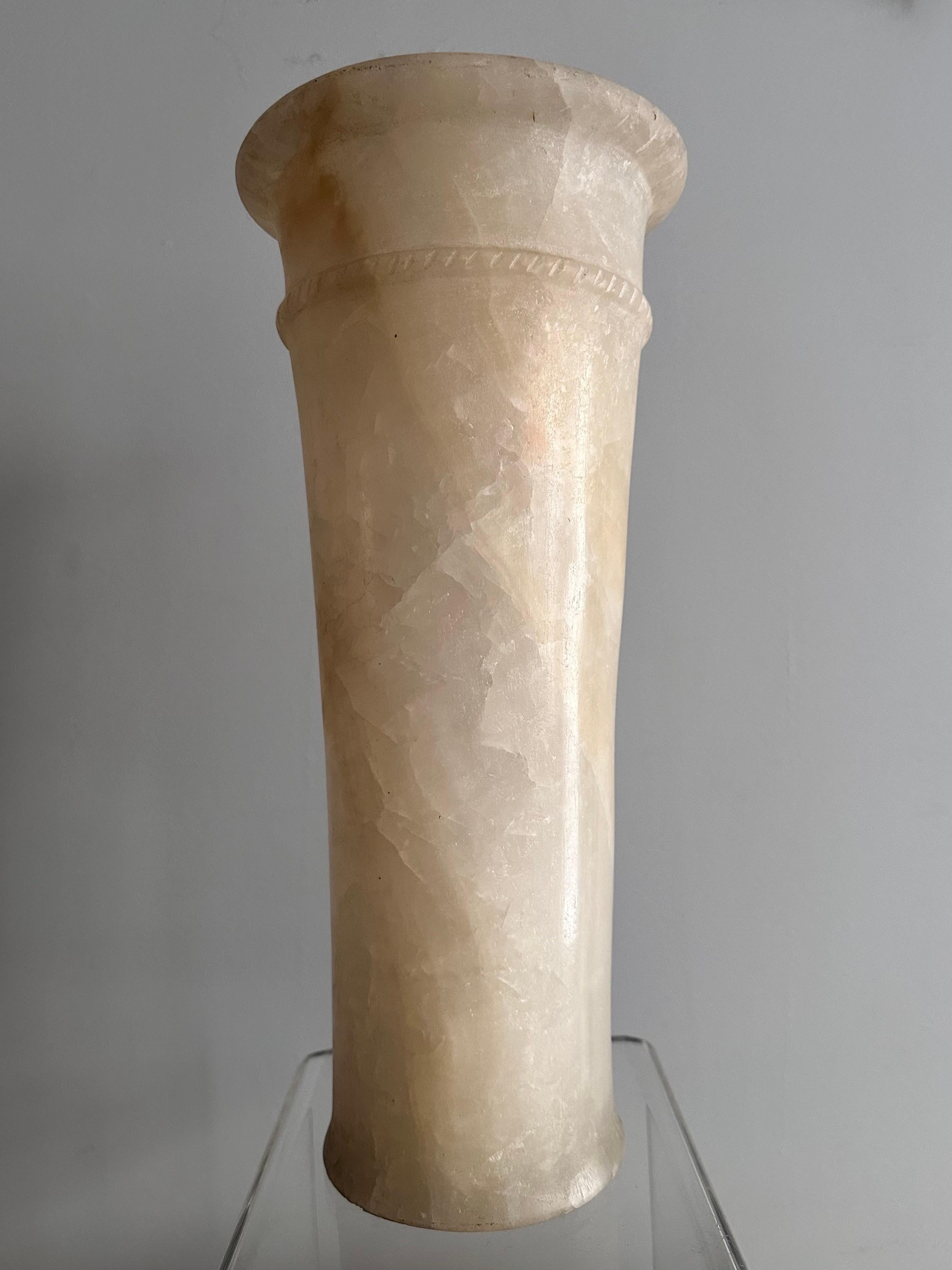Vase cylindrique en albâtre de style égyptien, 20e siècle.
Une base plane et un léger évasement  accentuée par un anneau segmenté en relief, à motif de corde, le tout sous un épais rebord annulaire.  
Hauteur 36,5 cm
