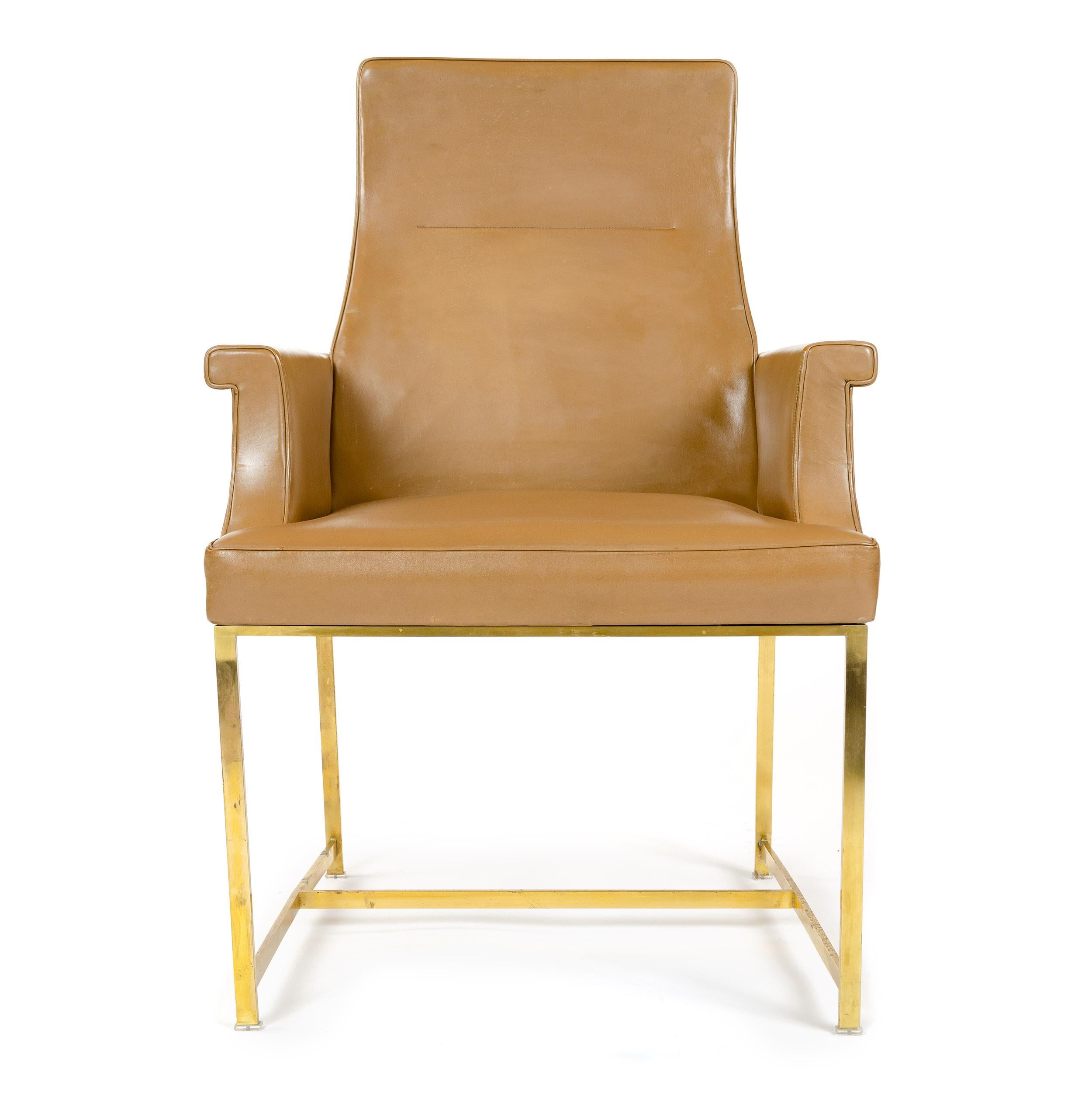 A high back armchair with the original tan leather upholstery and a solid brass base.